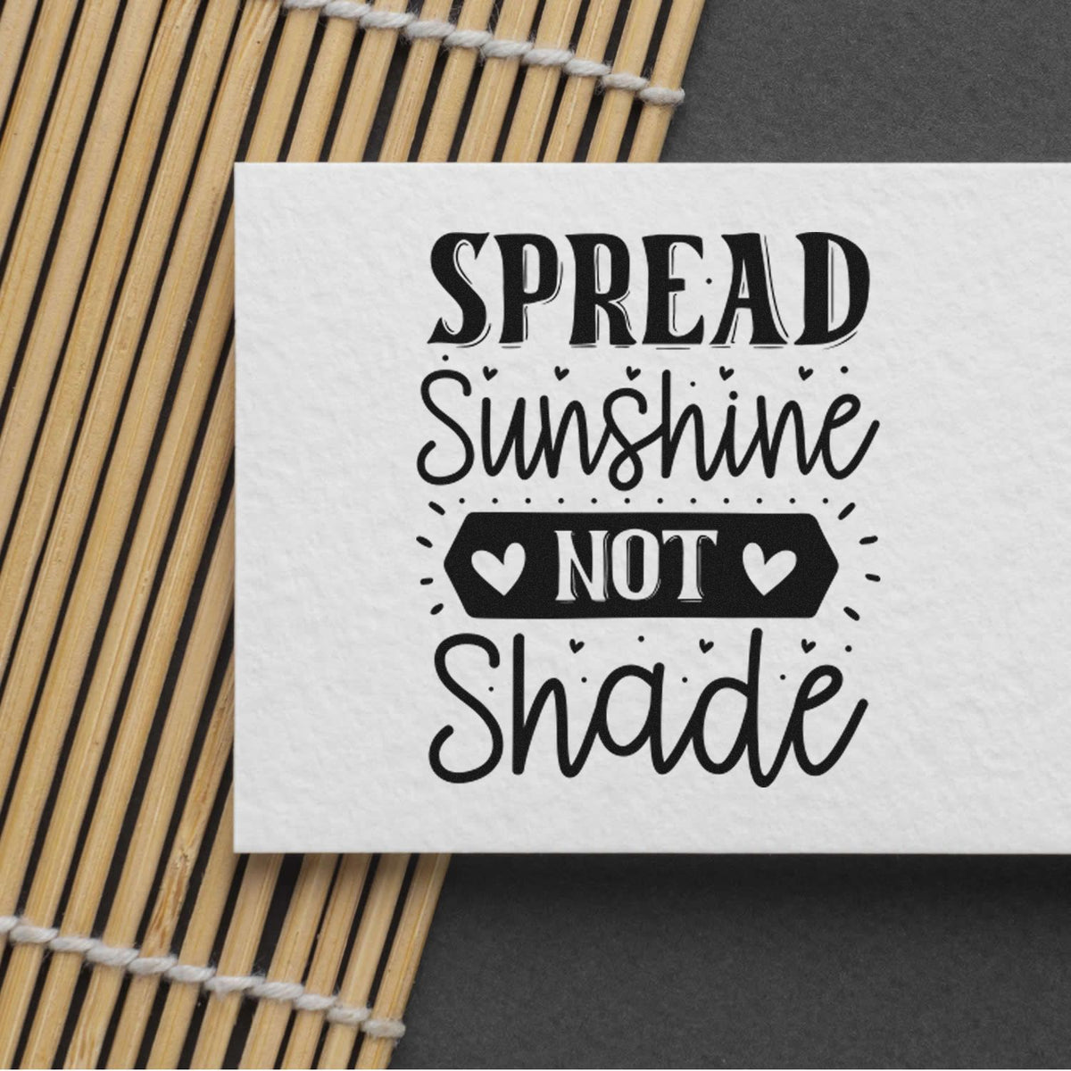 Black decorative rubber stamp and seal design reading Spread Sunshine Not Shade with hearts on white paper.
