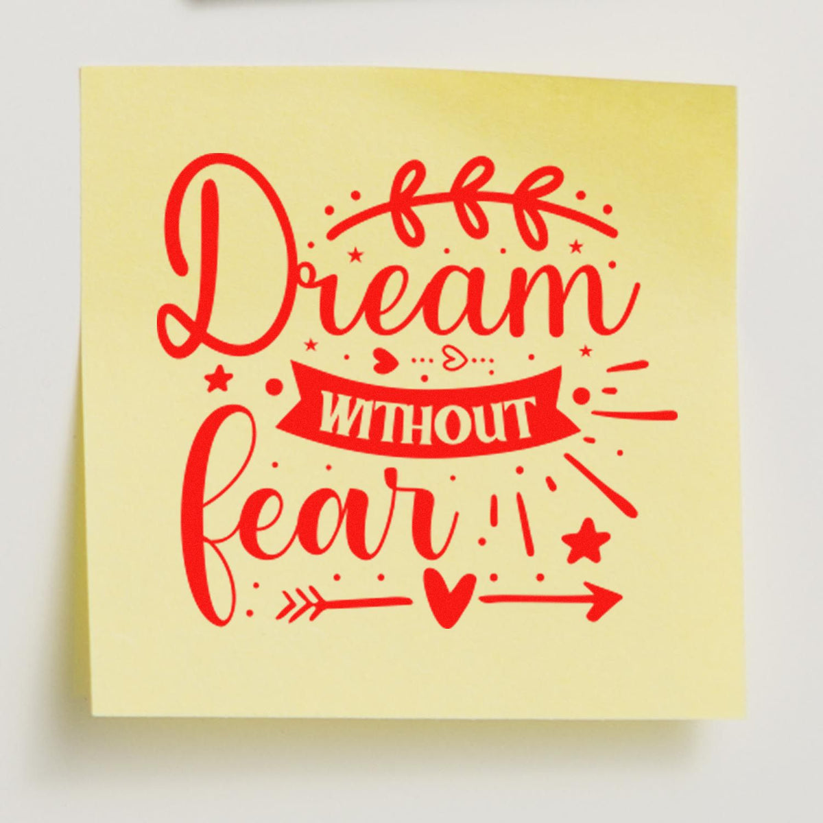 Yellow stamp seal with red Dream without fear lettering, stars, heart, and arrow accents.
