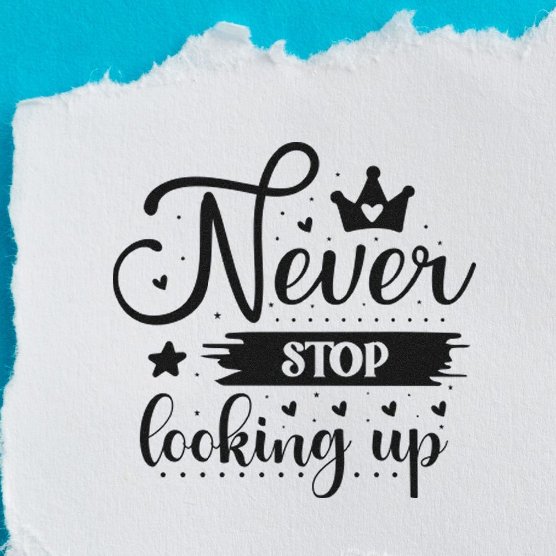 Black decorative stamp/seal with crown, hearts and stars reading Never stop looking up on white paper, turquoise background.