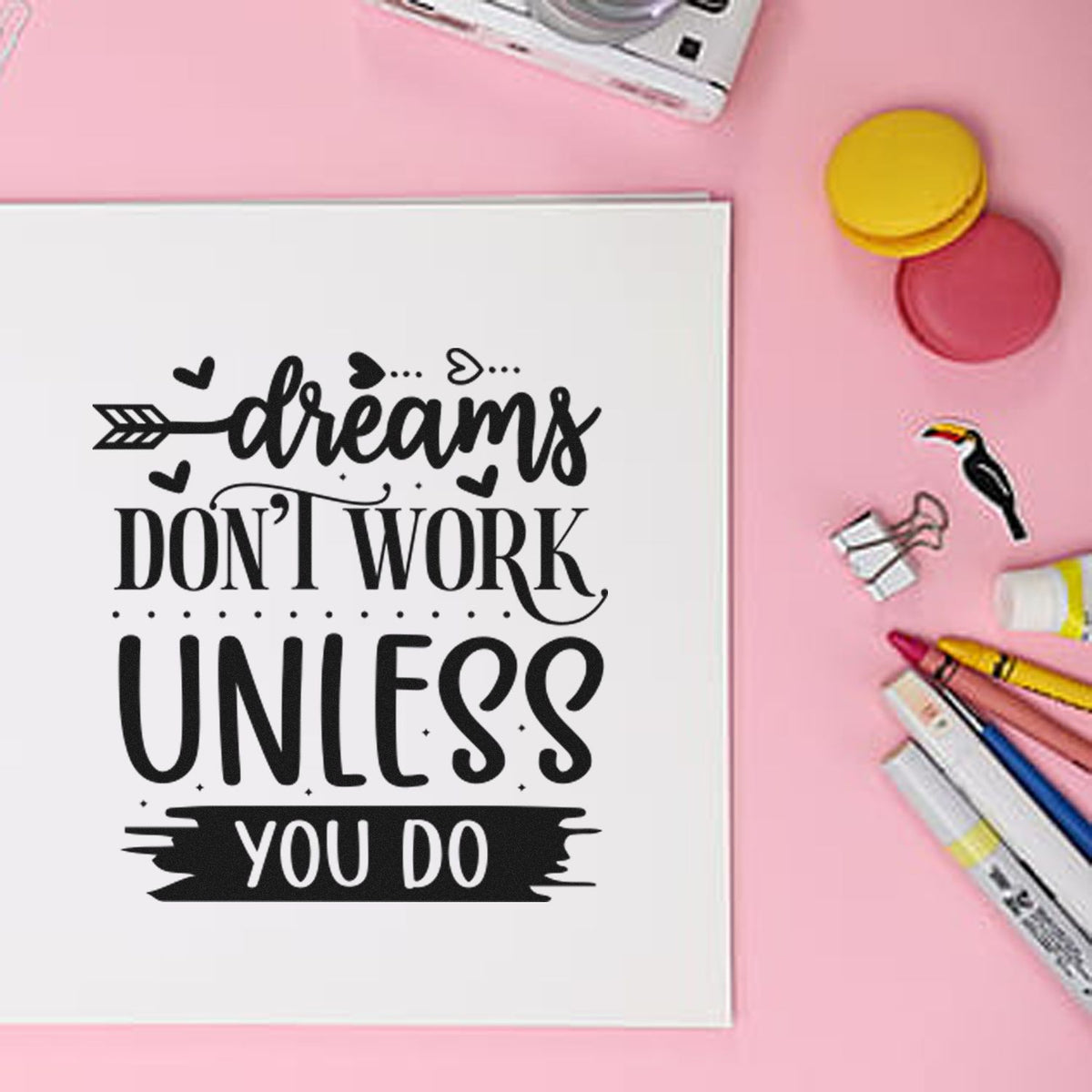 Black motivational stamp on white paper with pink background, plus colorful seal stamps, markers, and craft tools.