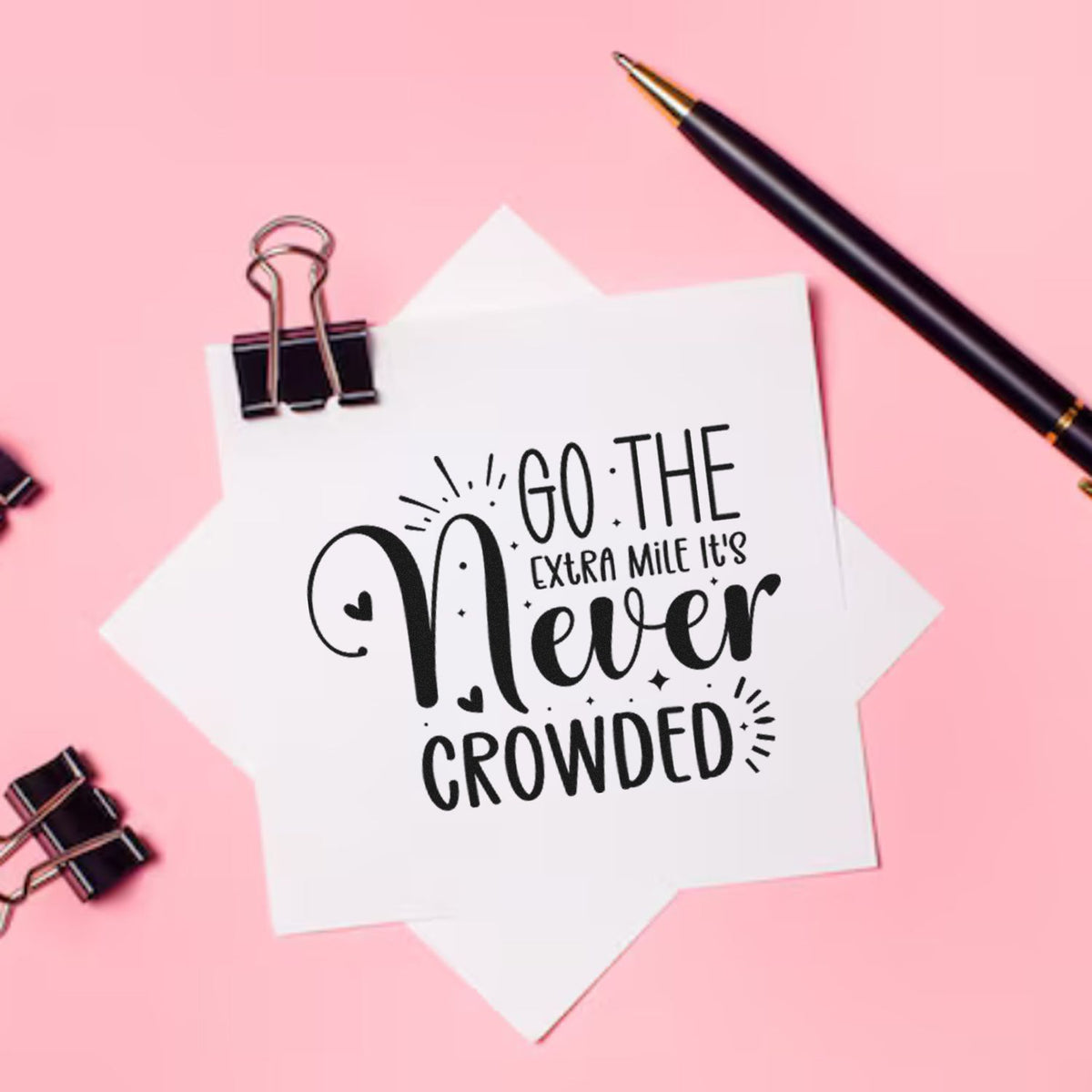 Custom stamp and seal design on white paper with black quote text, clipped with binder clips, on a pink background.