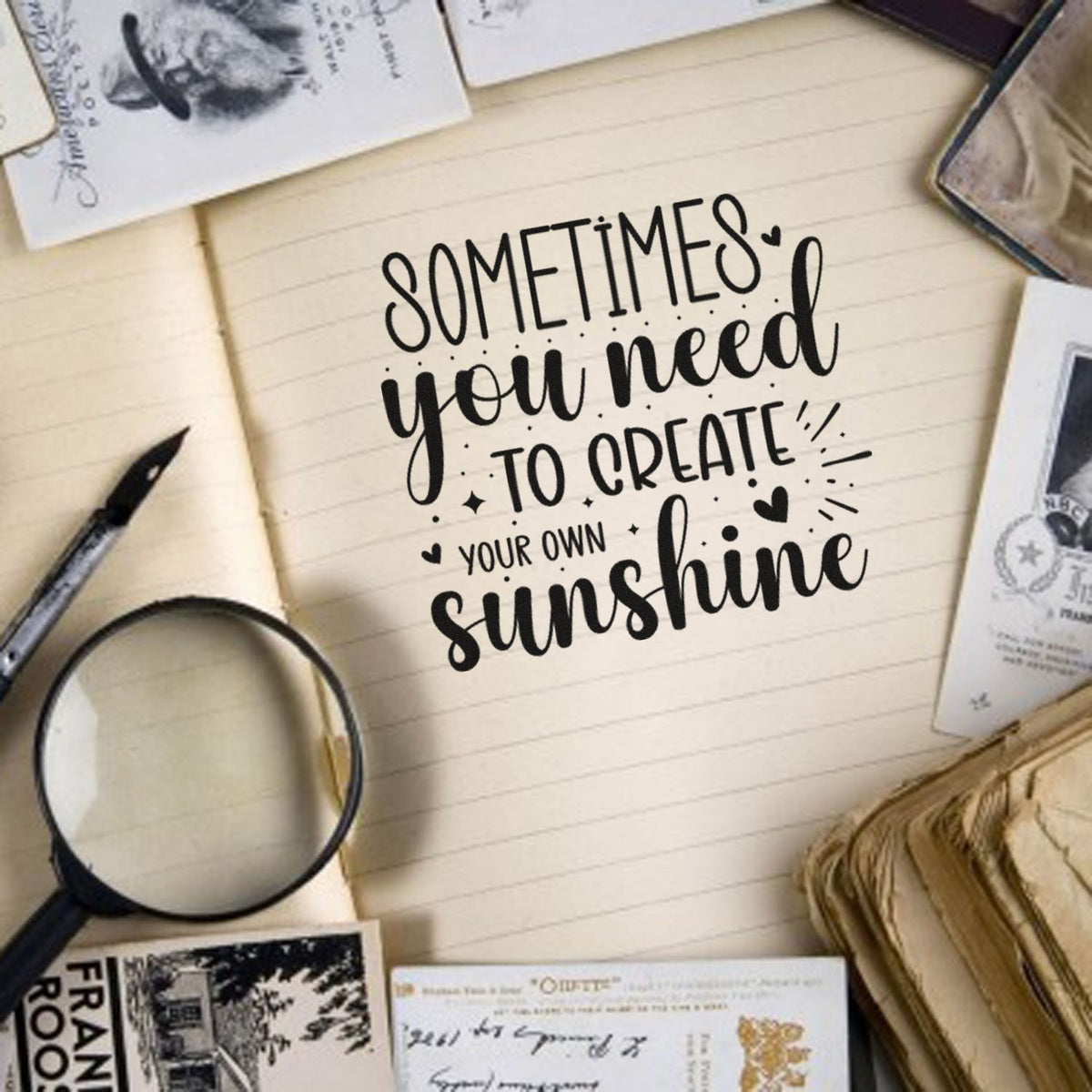 Black hand-lettered quote on a cream notebook, surrounded by stamp and seal products, a magnifying glass, and vintage paper cards.