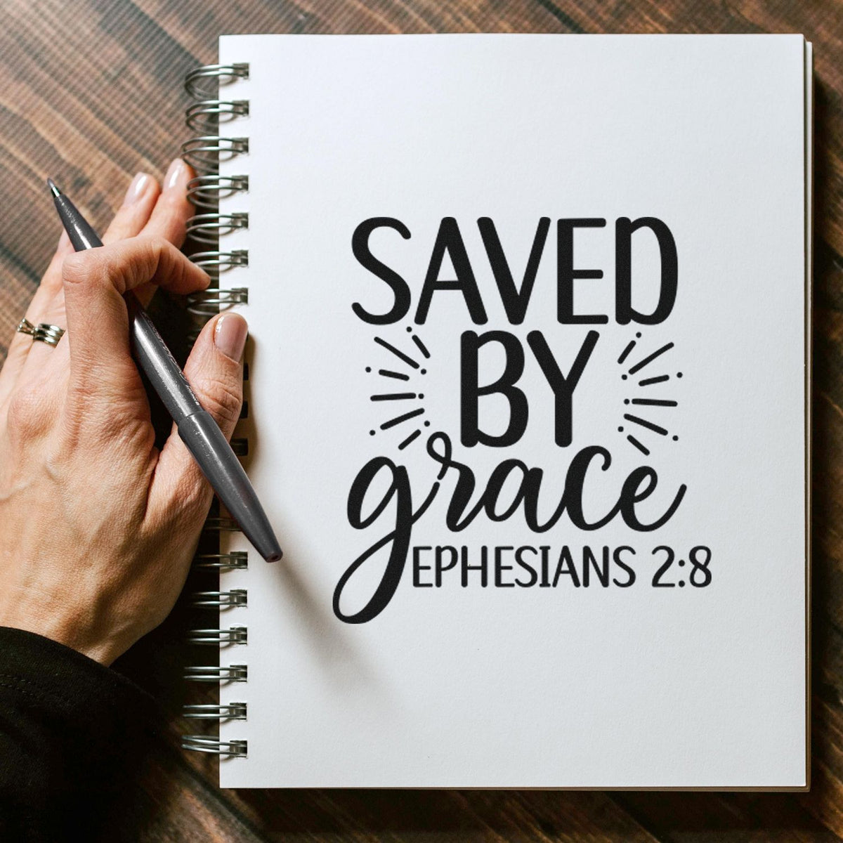 Vintage Pro Saved By Grace Ephesians Premium Wooden Stamp imprint stamped in black ink. The words "Saved by grace" appear with radiating lines and the scripture reference "Ephesians 2:8."