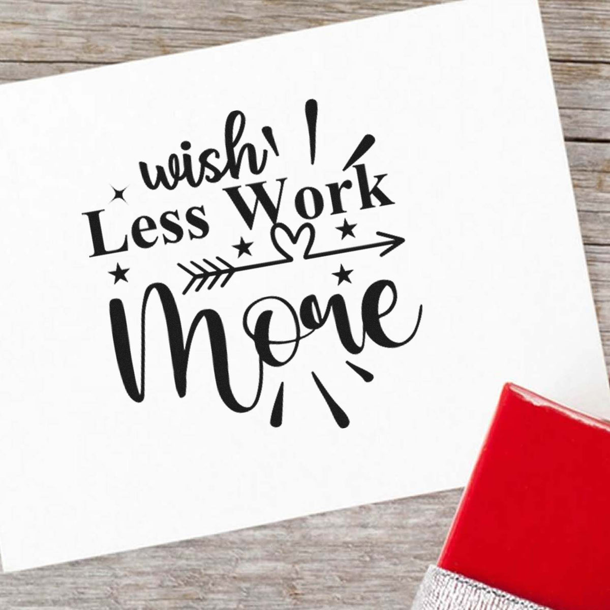 Black Wish Less Work More rubber stamp impression on white paper, with stars and arrow, beside a red seal block.