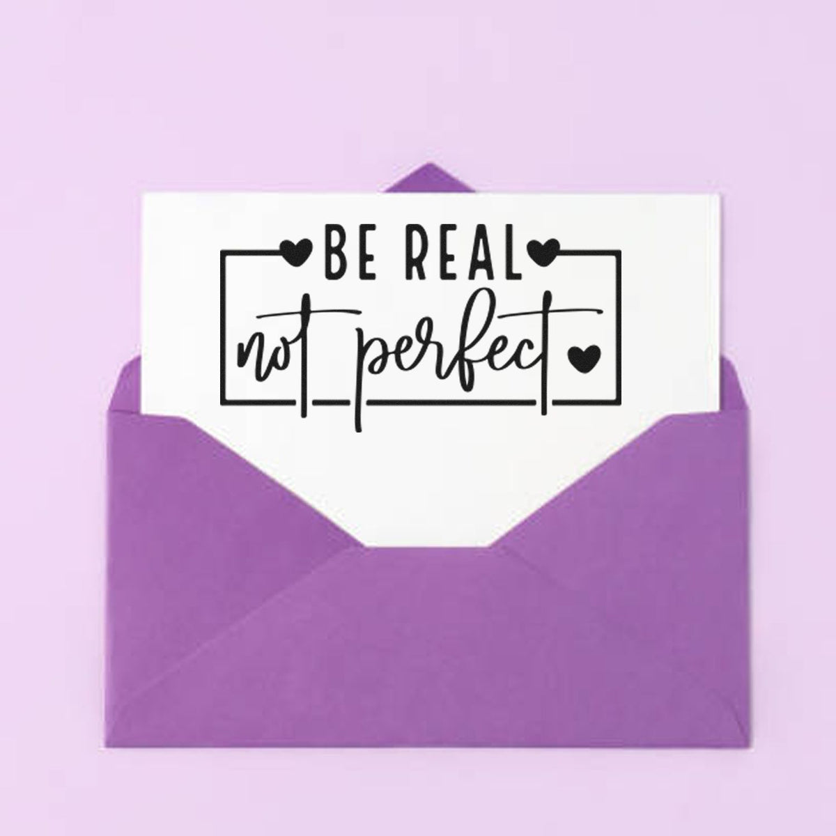 Purple envelope seal stamp with white label reading Be real not perfect in black script and heart accents.