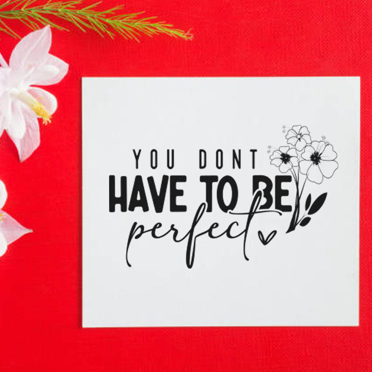 White stamp seal with black You Dont Have to Be Perfect floral design on bright red background