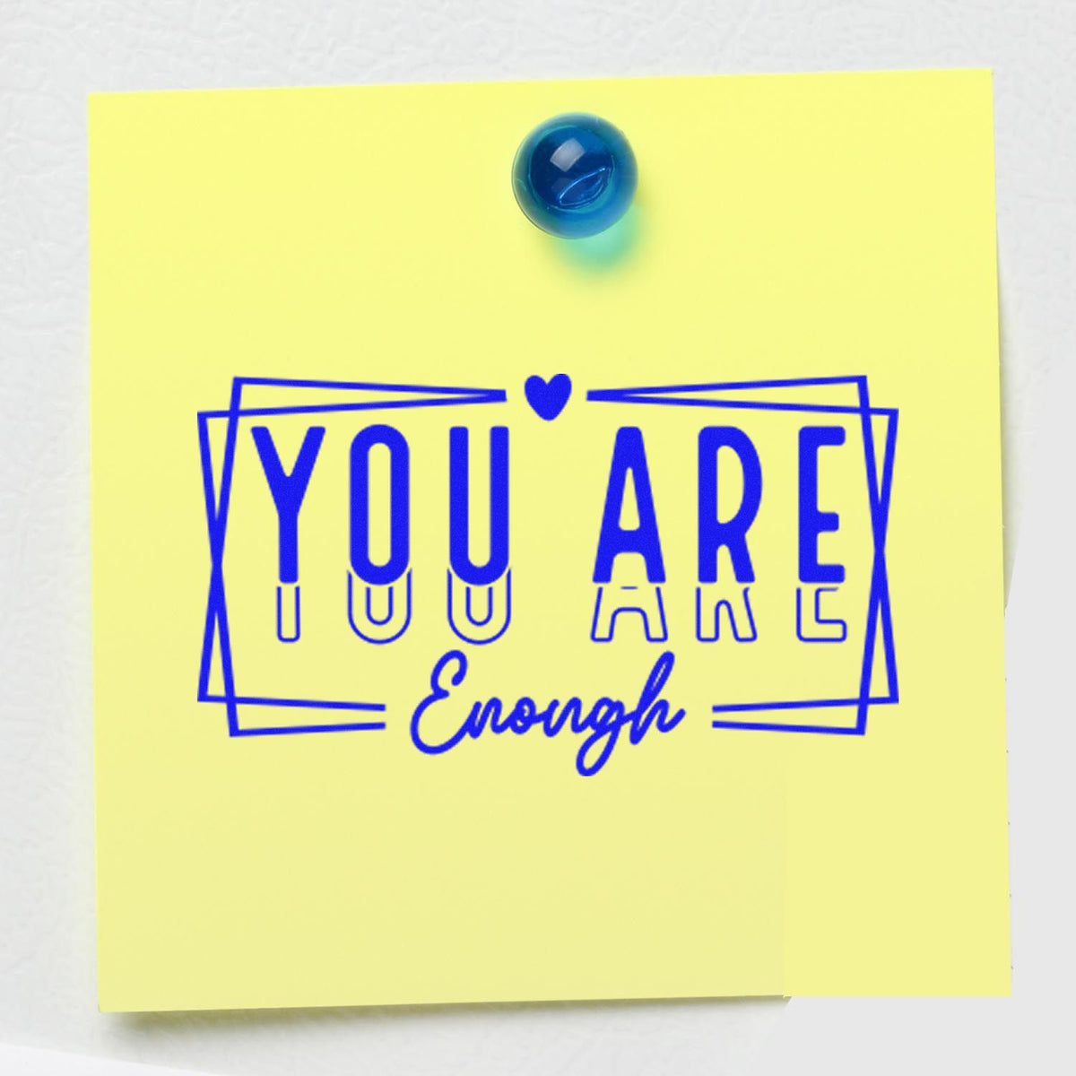 Blue custom stamp seal reading You Are Enough on a yellow note, with a heart and framed lettering.