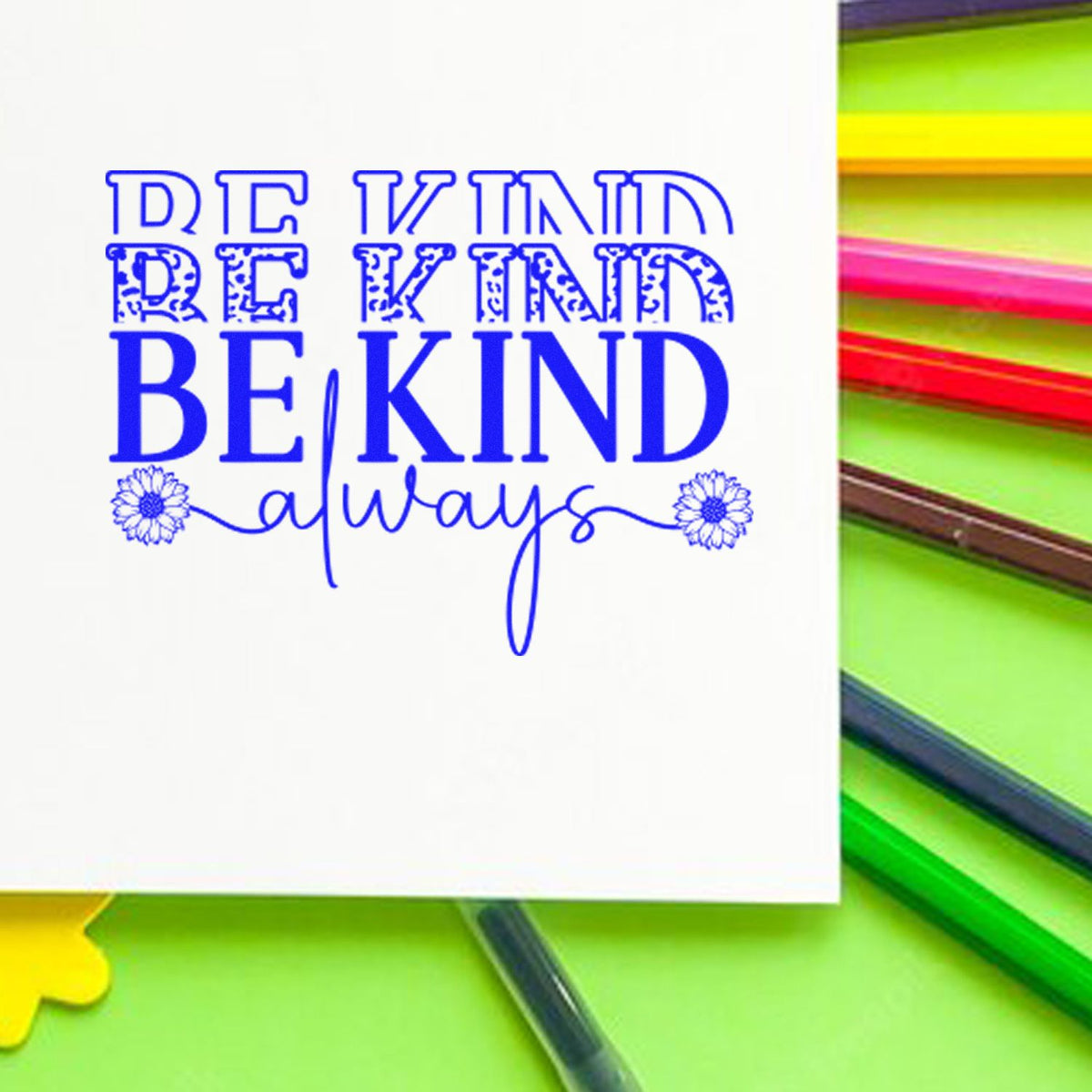 Blue Be Kind always stamp and seal design on white, with colorful pens and pencils in the background
