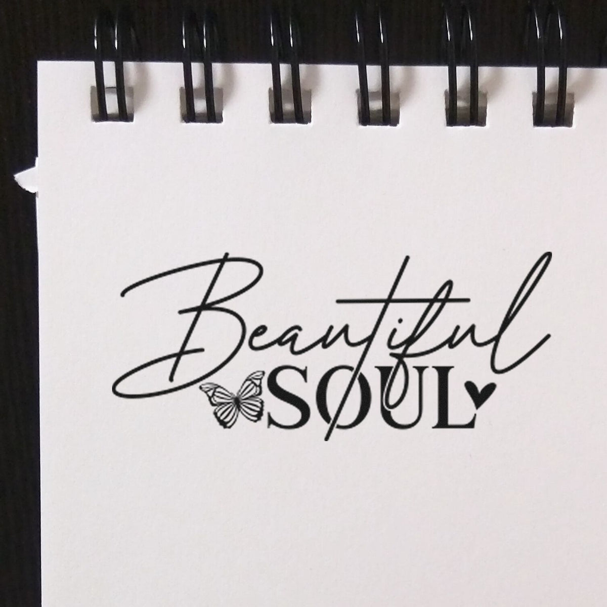 Black custom stamp and seal on white spiral-bound pad, reading Beautiful Soul with butterfly and heart in black.