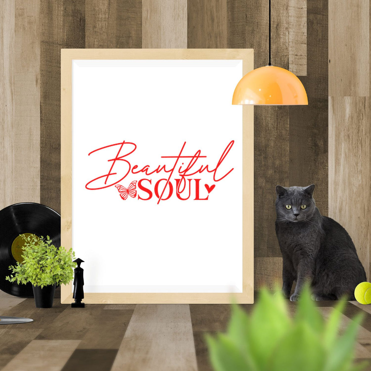 Red Beautiful Soul stamp and seal design on white, framed in wood, with a black cat and orange pendant lamp.