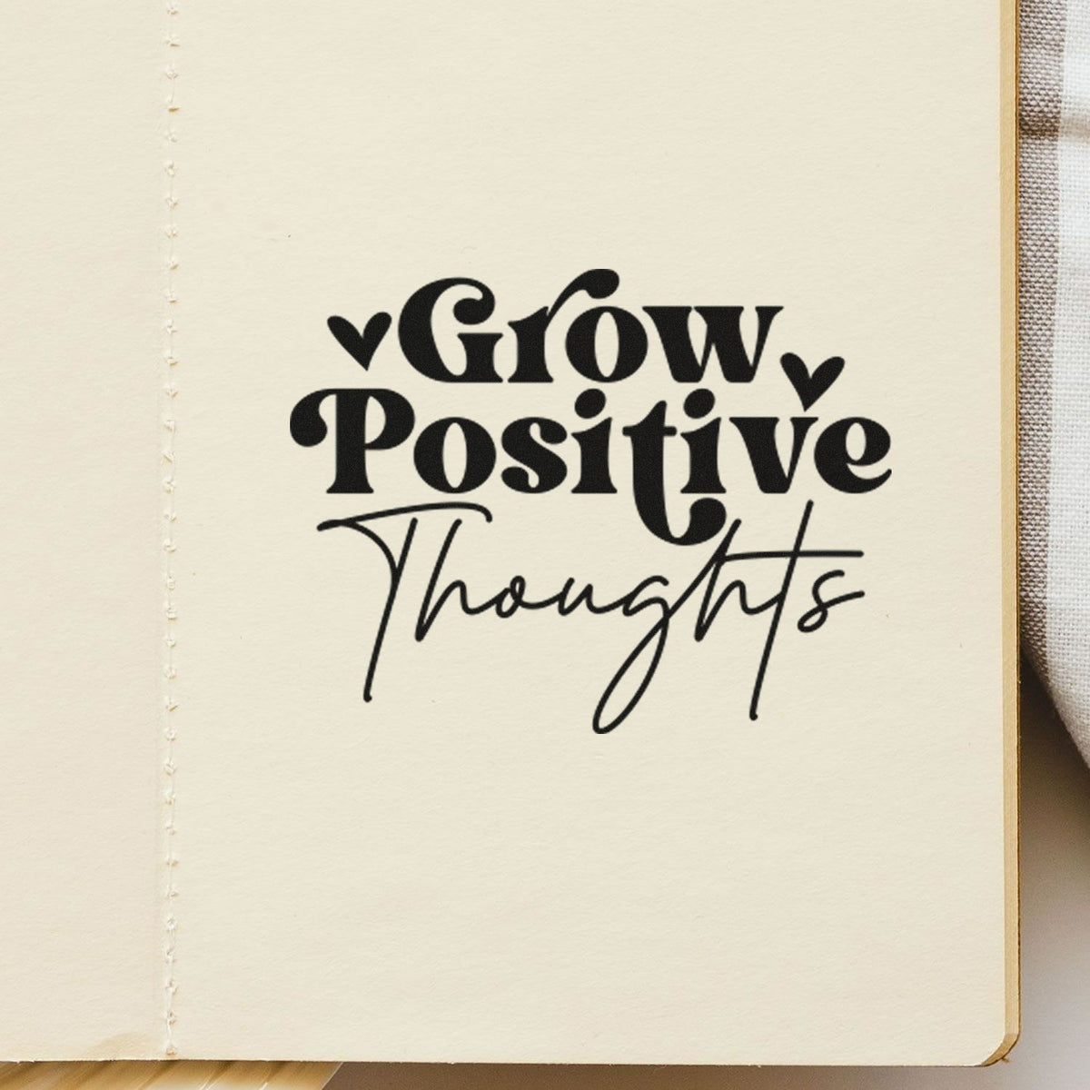 Black Grow Positive Thoughts stamp with hearts on cream notebook paper, ideal for seal and stamp products.