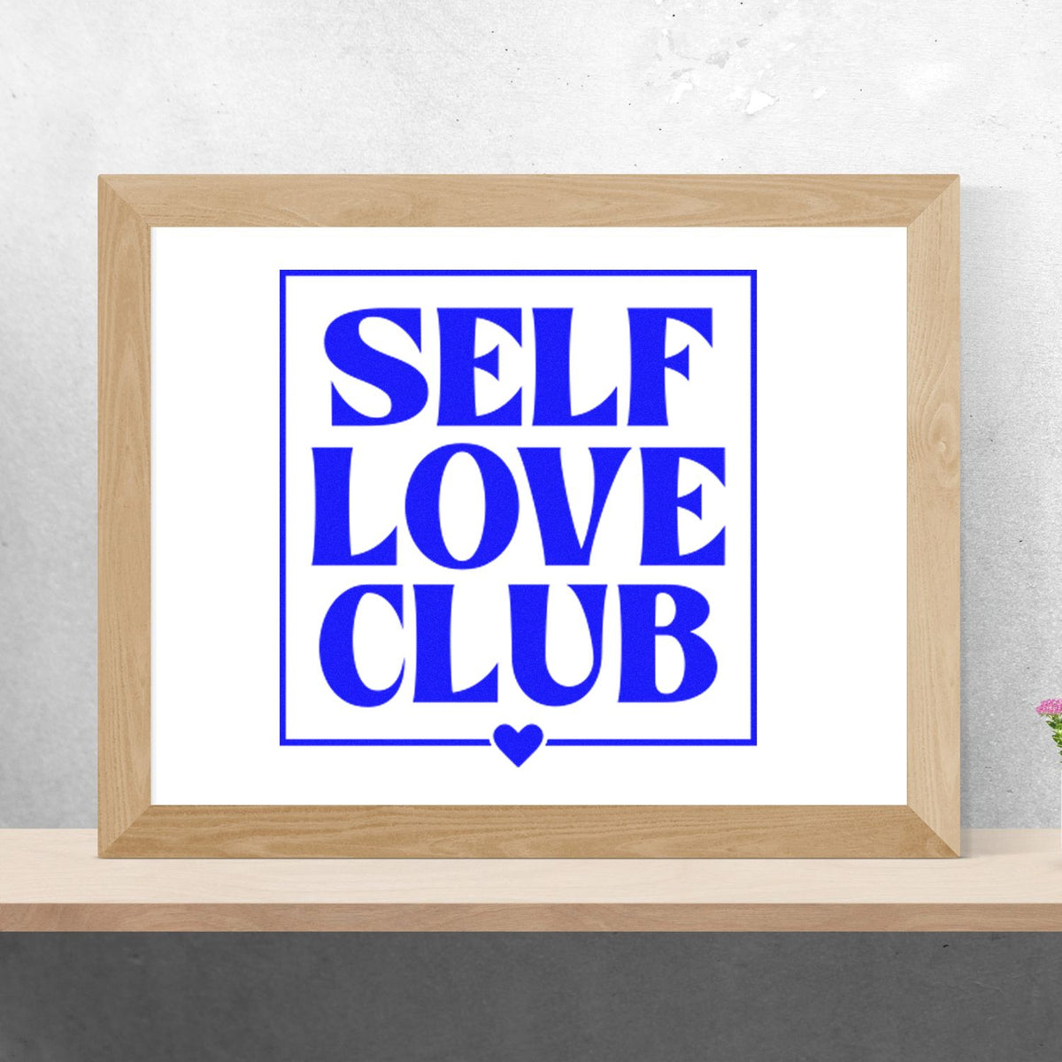 Blue SELF LOVE CLUB stamp-style seal in a wooden frame with a small heart on a white background.