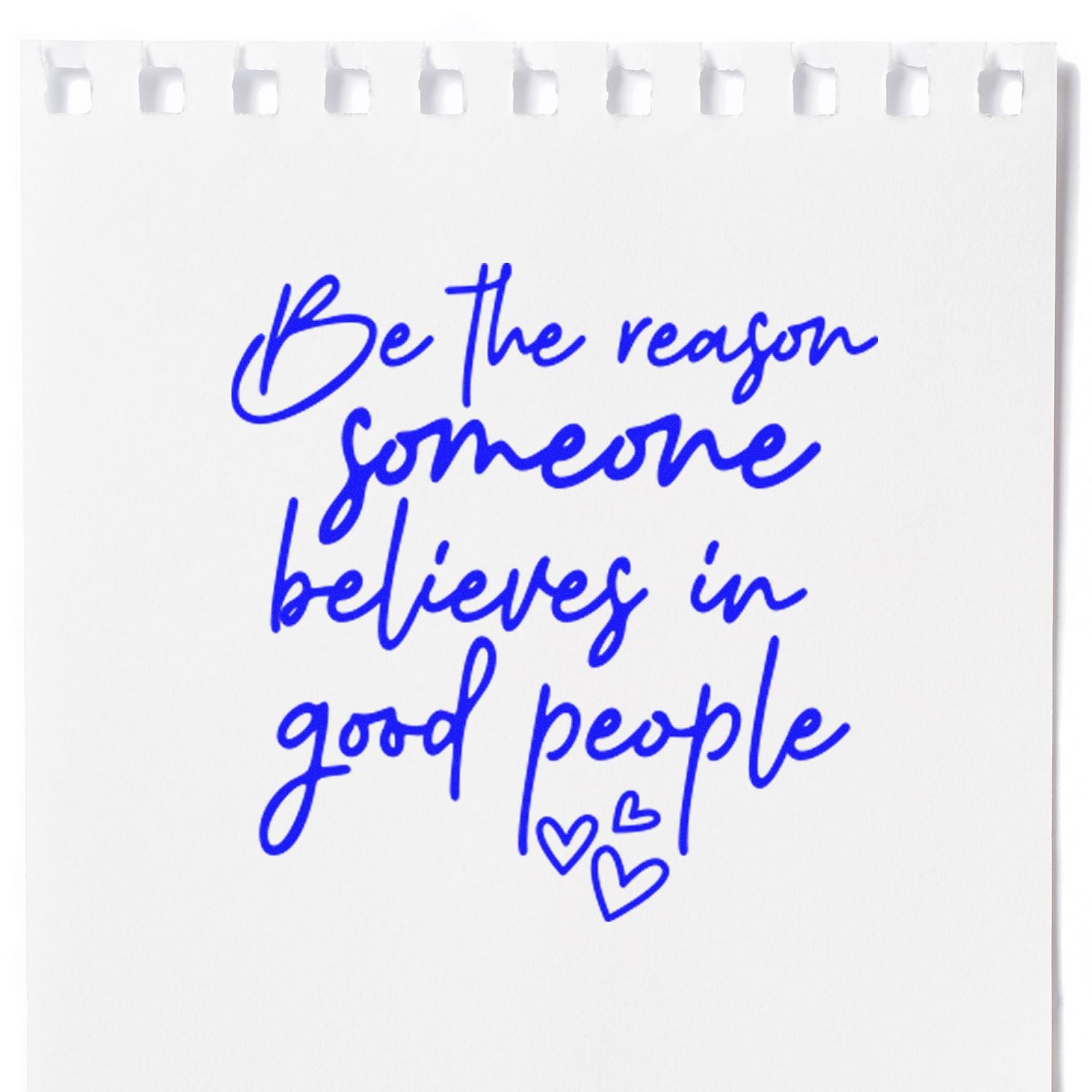 Blue handwritten stamp design on white paper reading Be the reason someone believes in good people with small hearts.