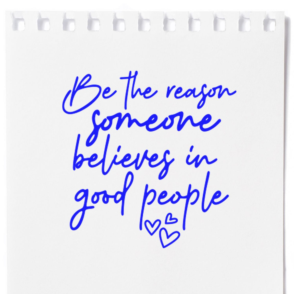 White notepad with blue stamp-style handwritten quote, Be the reason someone believes in good people, and small hearts.