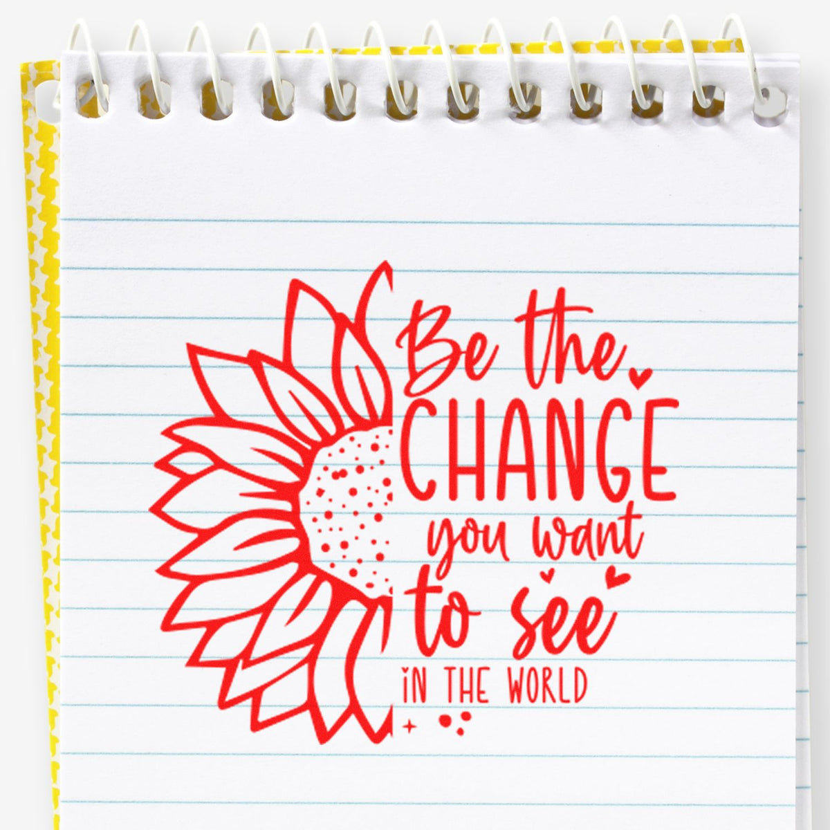 Red decorative stamp/seal on lined spiral notepad, with sunflower design, yellow border, and quote Be the change you want to see.