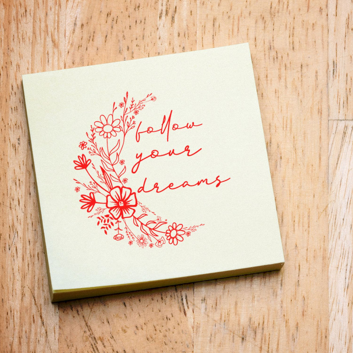 Cream stamp pad with red floral follow your dreams seal design on a wood background