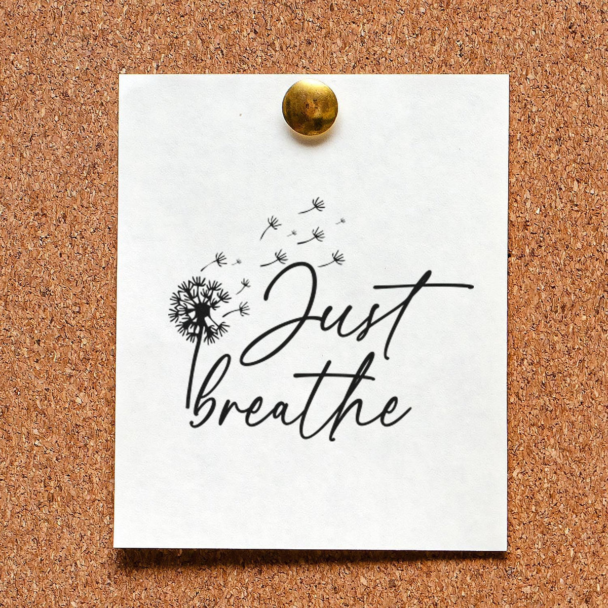 White stamp and seal sample card pinned to corkboard, black Just breathe script with dandelion seeds, brass tack.