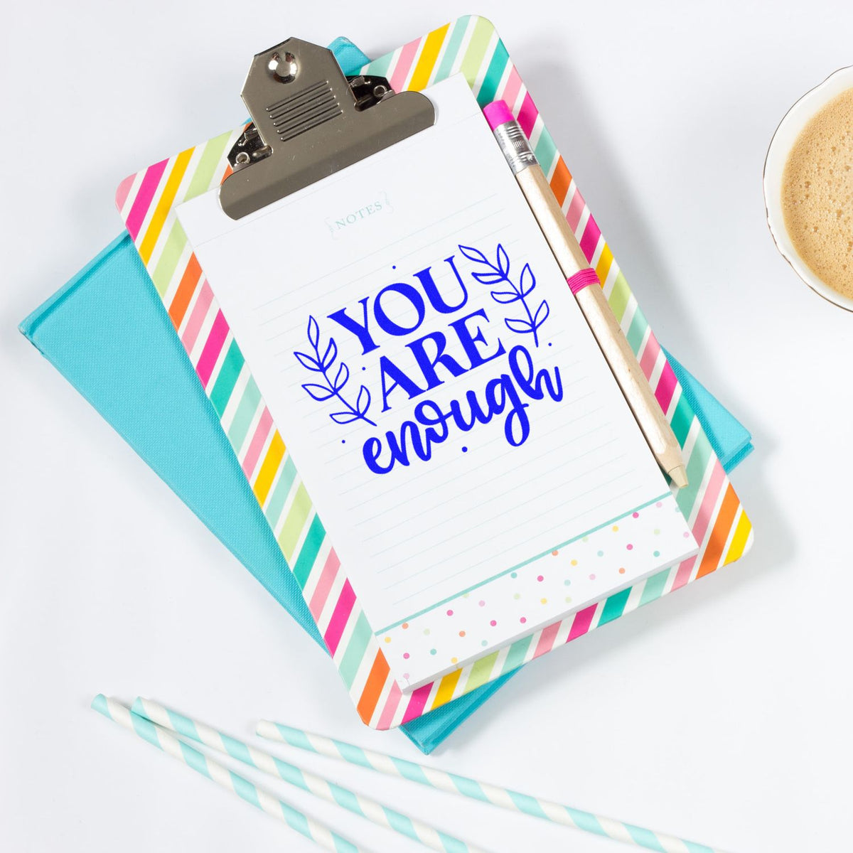 Colorful clipboard notepad with blue You Are Enough custom stamp and seal, striped border, pastel notebook, pencil, and coffee cup.