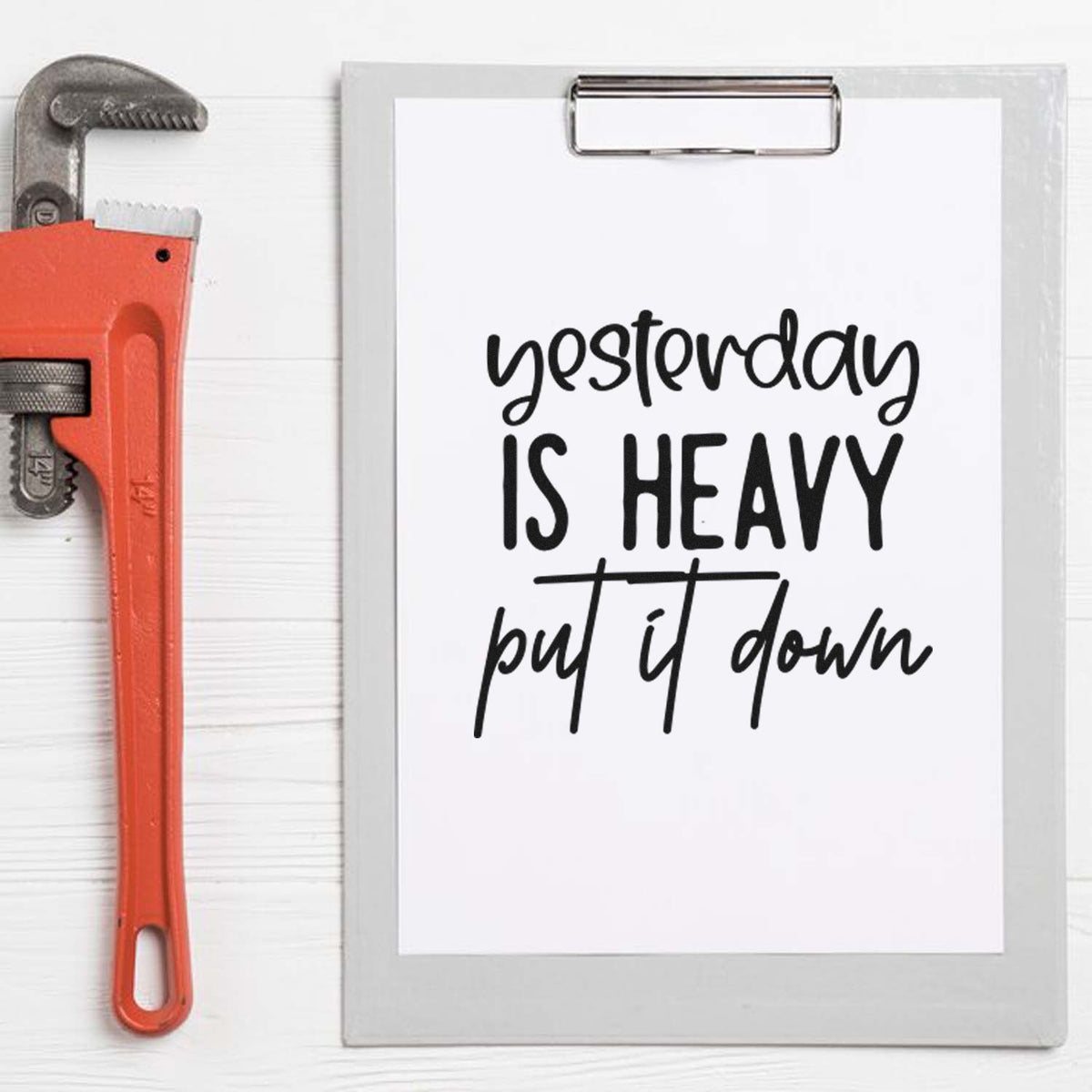 Orange stamp and gray seal products beside a clipboard with black yesterday is heavy, put it down lettering.