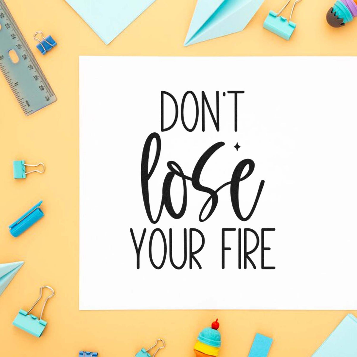 Custom stamp and seal design with DONT lose your FIRE in black, framed by pastel blue stationery, binder clips, ruler, and paper planes.