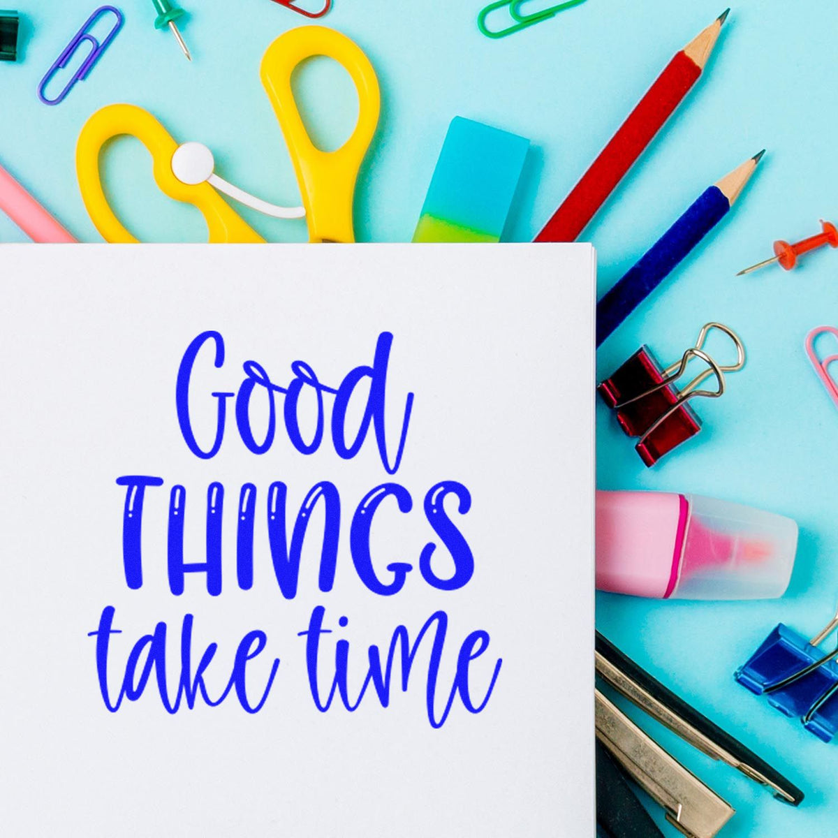 White card with blue Good things take time, surrounded by colorful stamp and seal products, pencils, clips, and erasers.