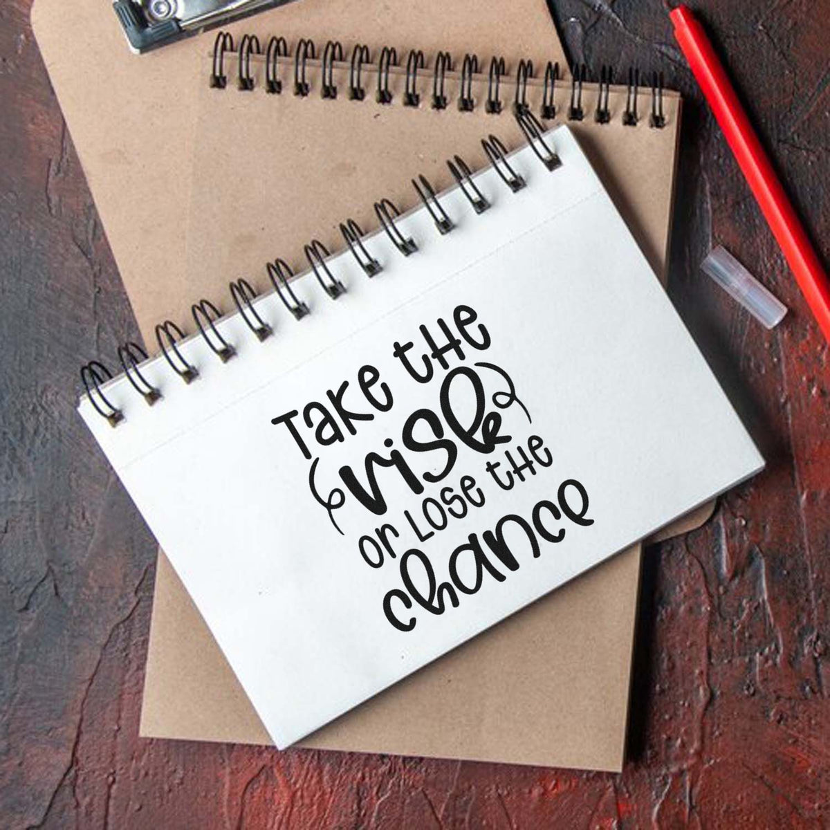 Custom stamp and seal notebook set with black Take the risk or lose the chance lettering on white spiral journal and brown kraft pad.