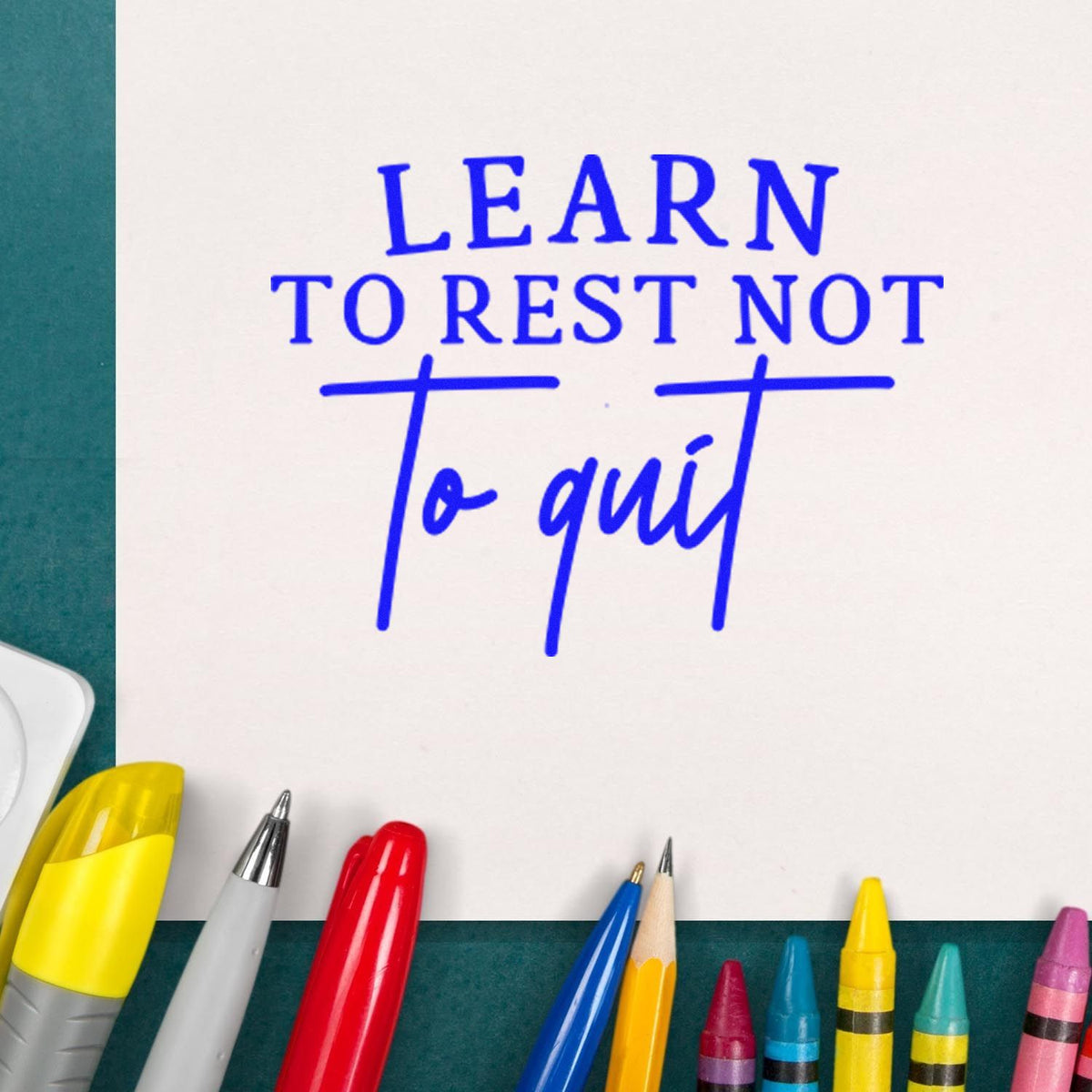 Blue motivational stamp and seal reading Learn to rest not to quit on white paper, framed by colorful pens.