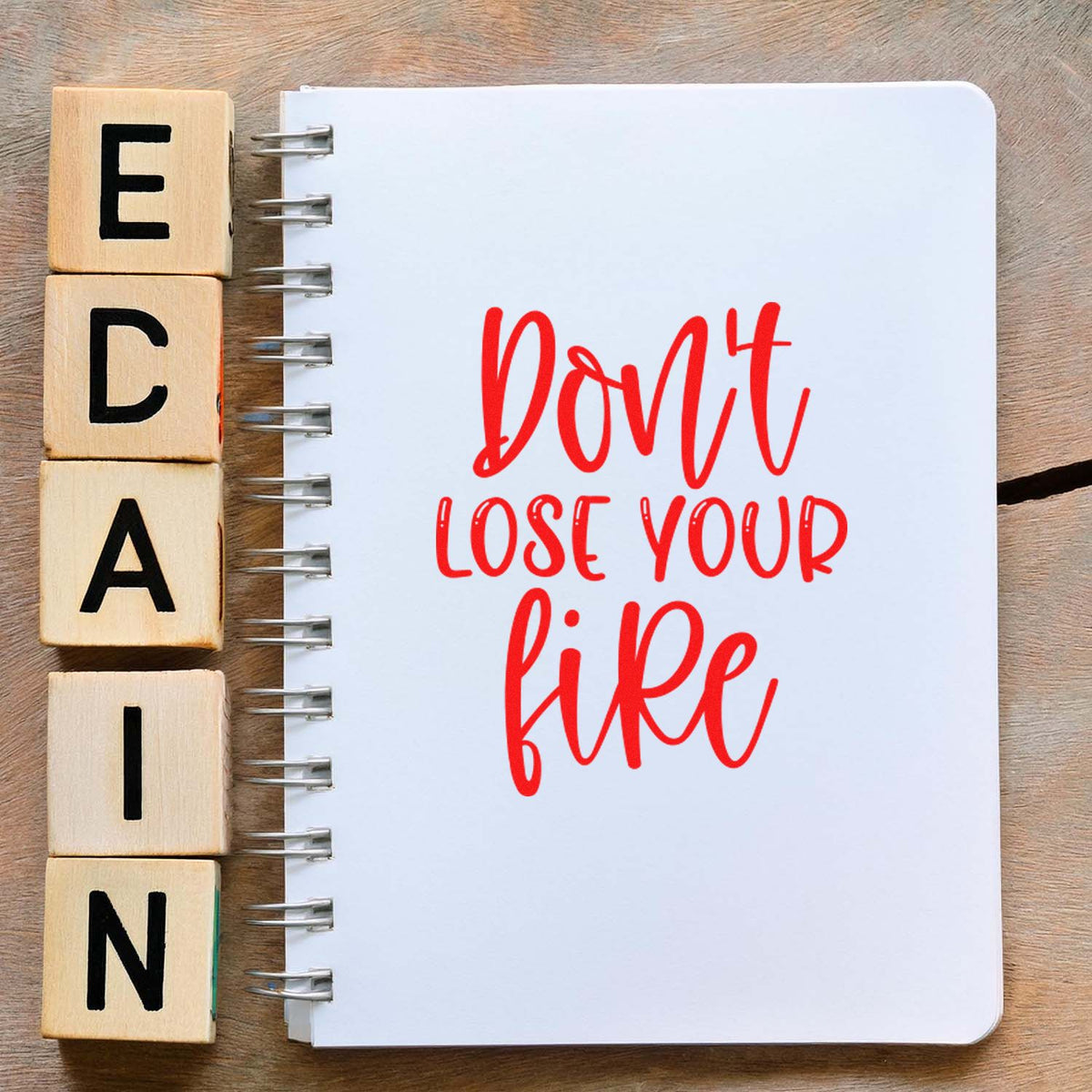 Wooden letter stamp blocks spelling CLEAN beside a white spiral notebook with red Dont lose your fire lettering.