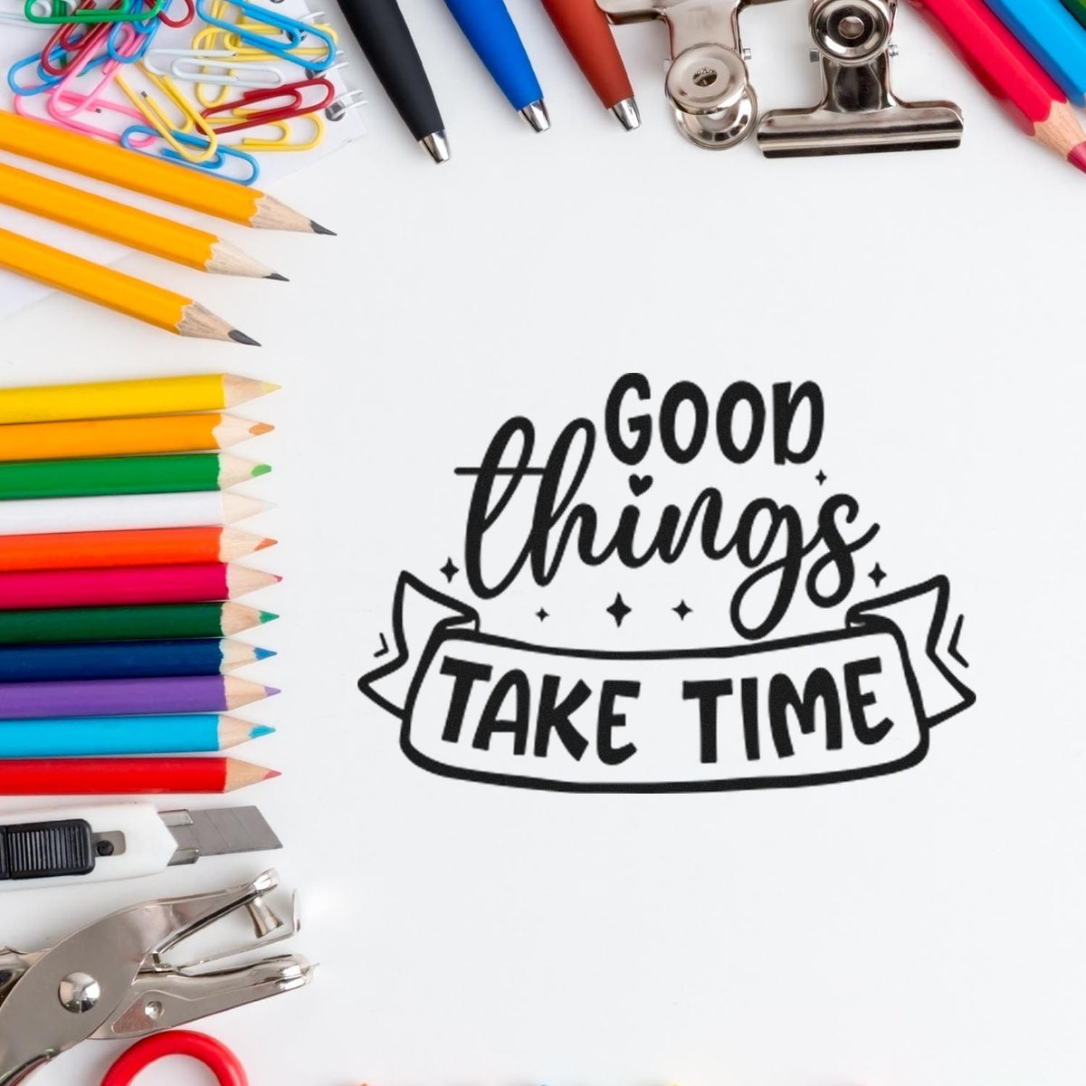 Black Good Things Take Time stamp seal surrounded by colorful pencils, paper clips, binder clips, and craft tools on white.