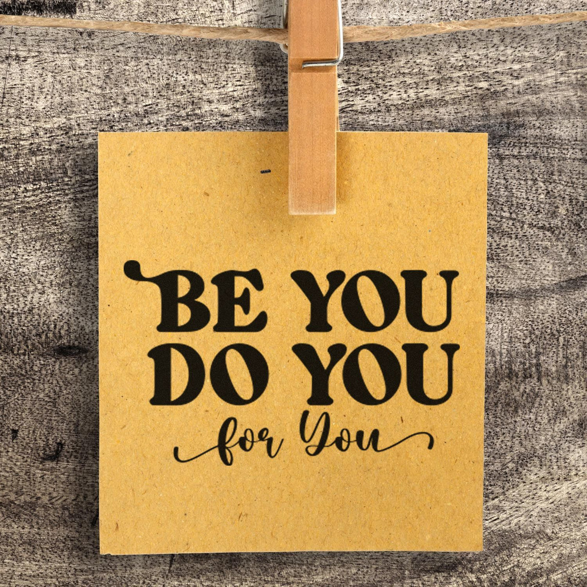 Kraft paper gift tag with black Be You Do You for You stamp, clipped to rustic wood background with a wooden clothespin.