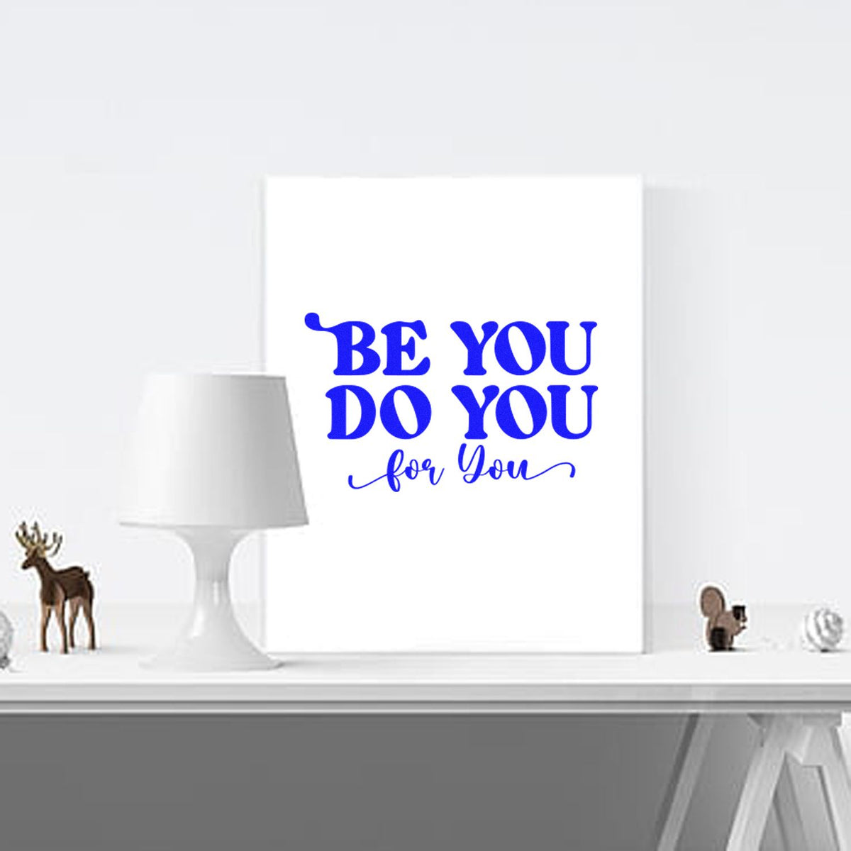 Blue custom stamp and seal design reading Be You Do You for You on a white canvas, styled with a white lamp and decor.