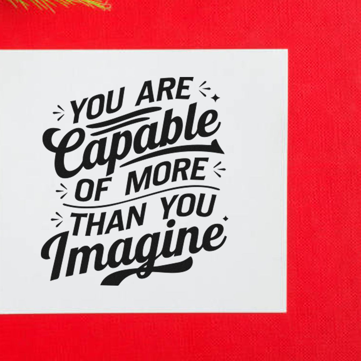 Black motivational stamp and seal design reading You are capable of more than you imagine on a white square, red background.