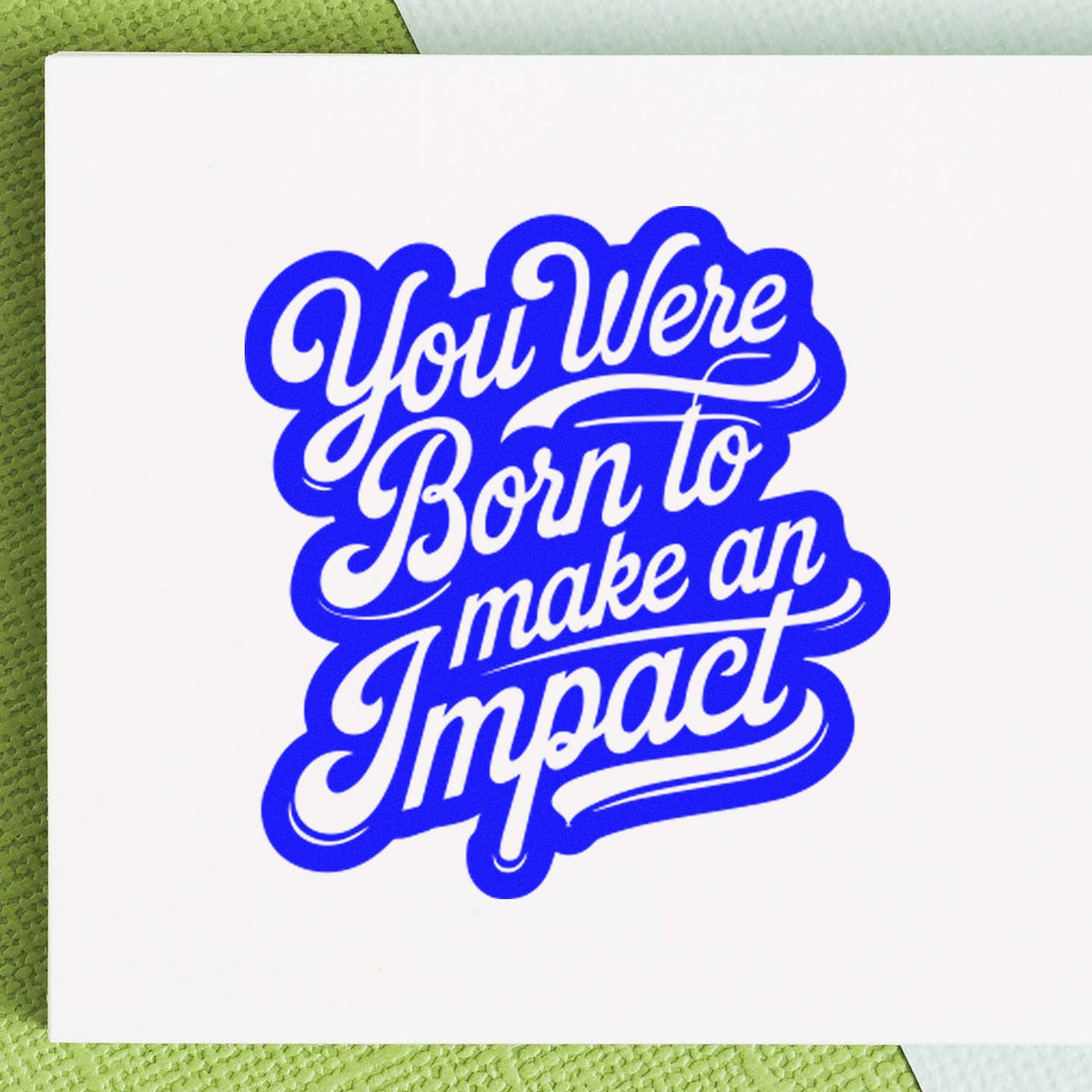 Blue custom rubber stamp seal with script text, You Were Born to make an Impact, on white paper.