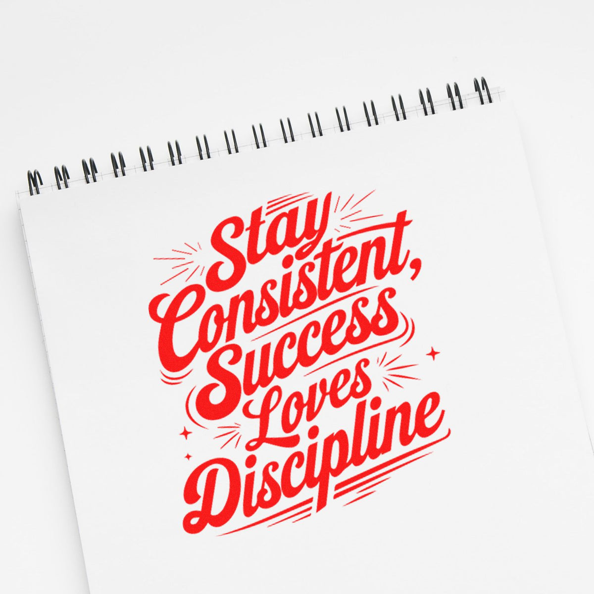 Red custom stamp and seal design on white spiral notebook reading Stay consistent, Success Loves Discipline