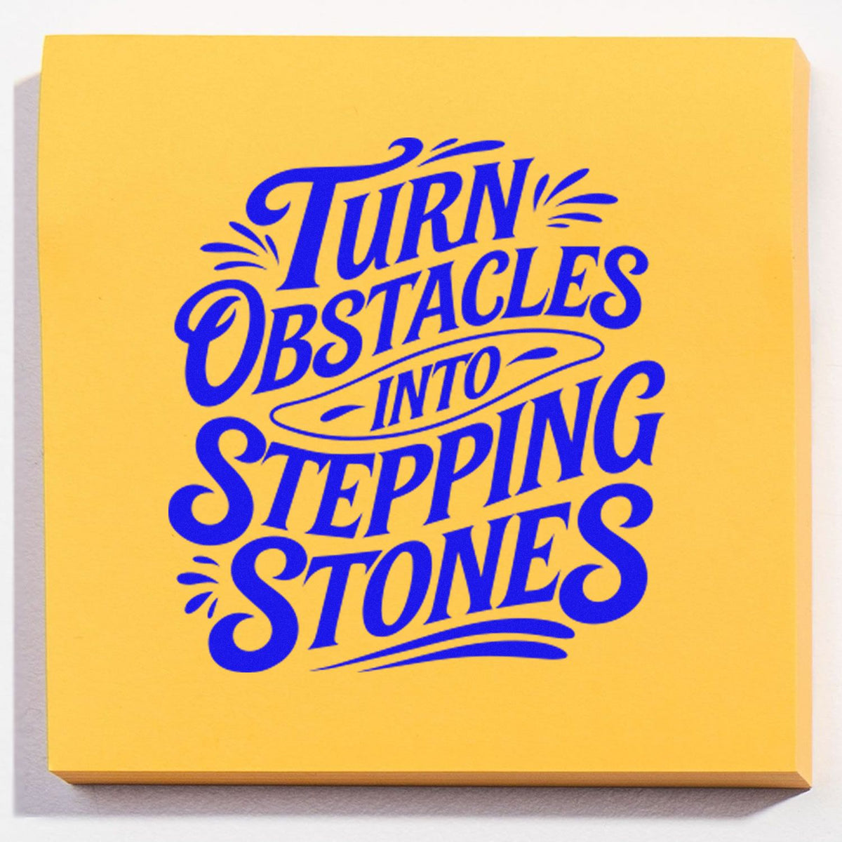 Yellow stamp and seal pad with bold blue lettering reading Turn Obstacles Into Stepping Stones.