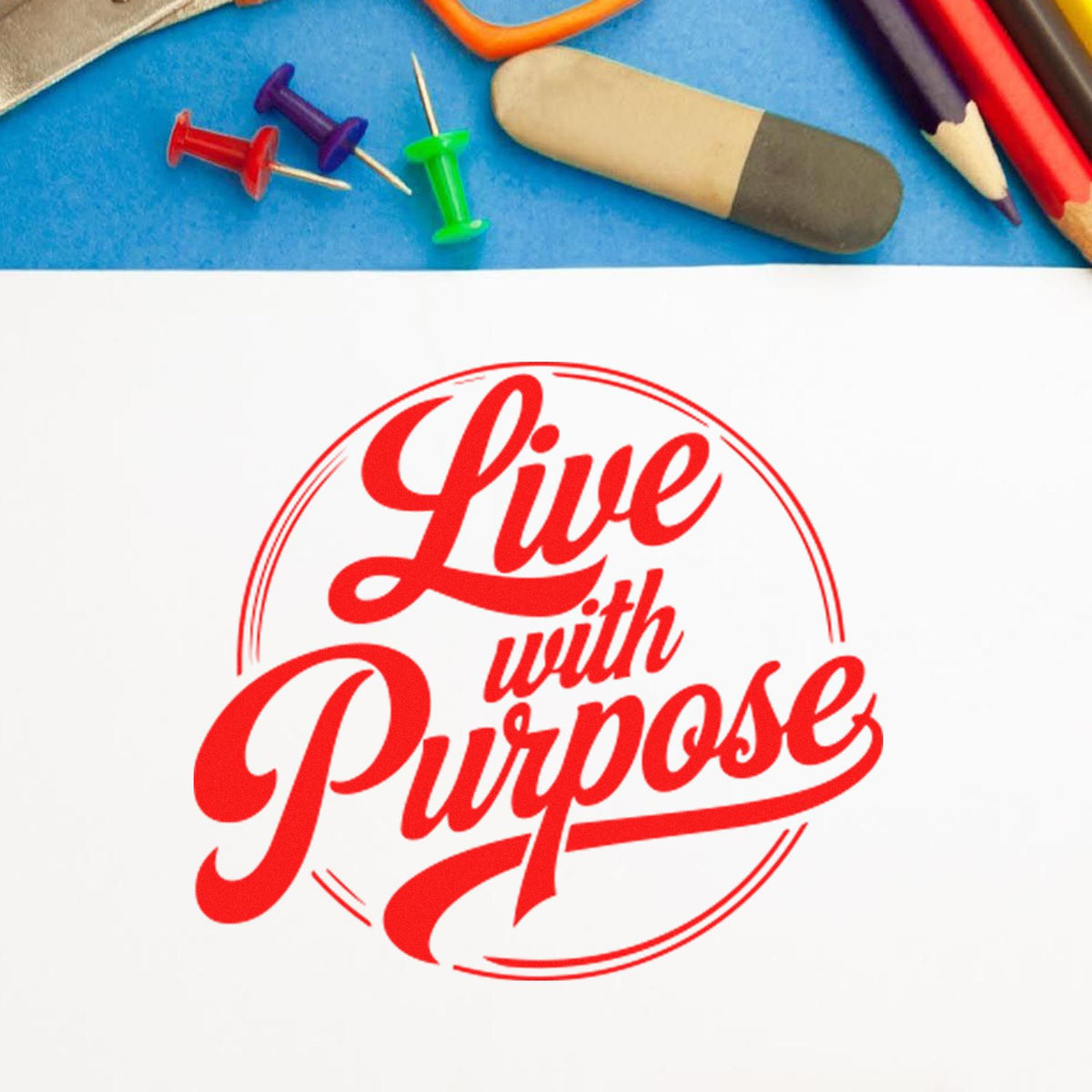 Red Live with Purpose stamp seal on white paper, with push pins, eraser and colored pencils on a blue background.