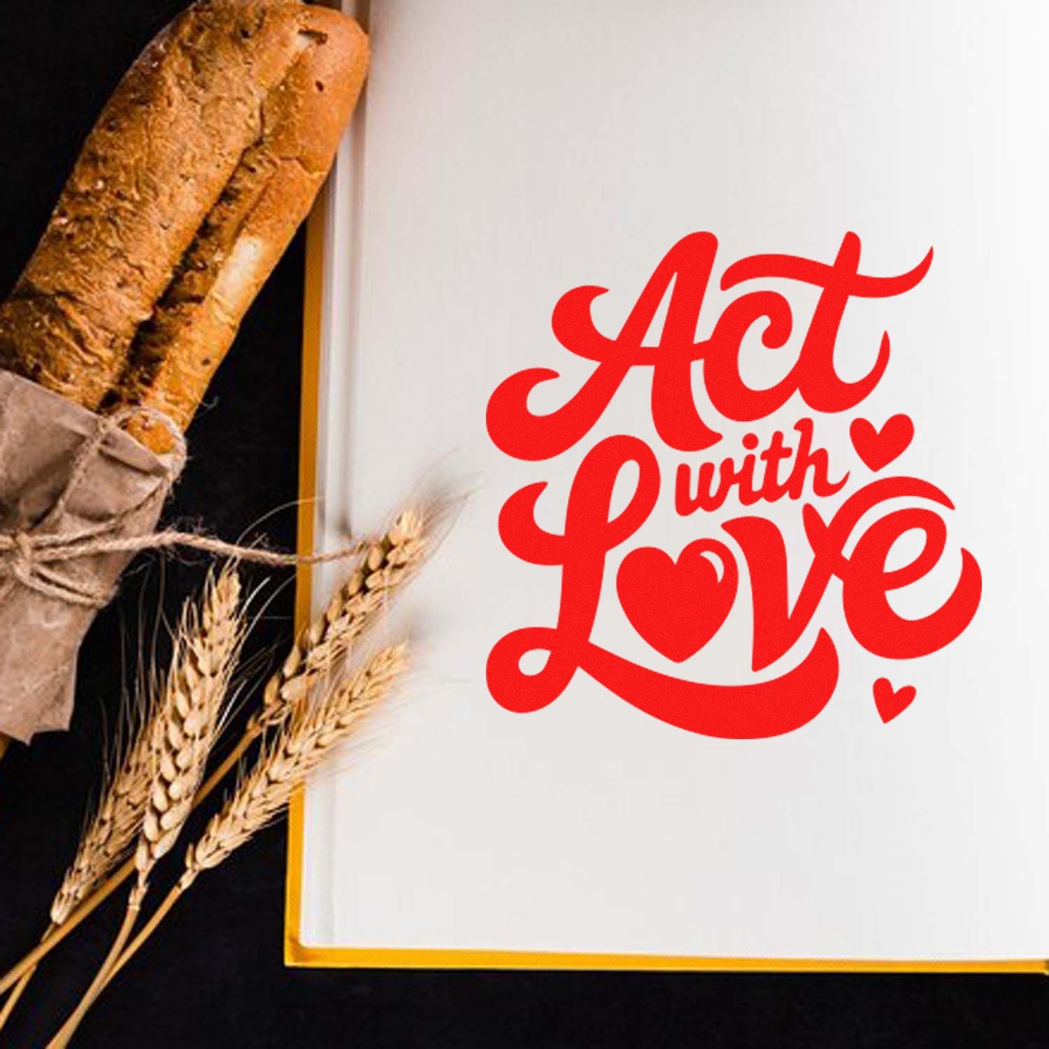 Red Act with Love stamp and seal on white paper, beside a rustic baguette and wheat stalks.