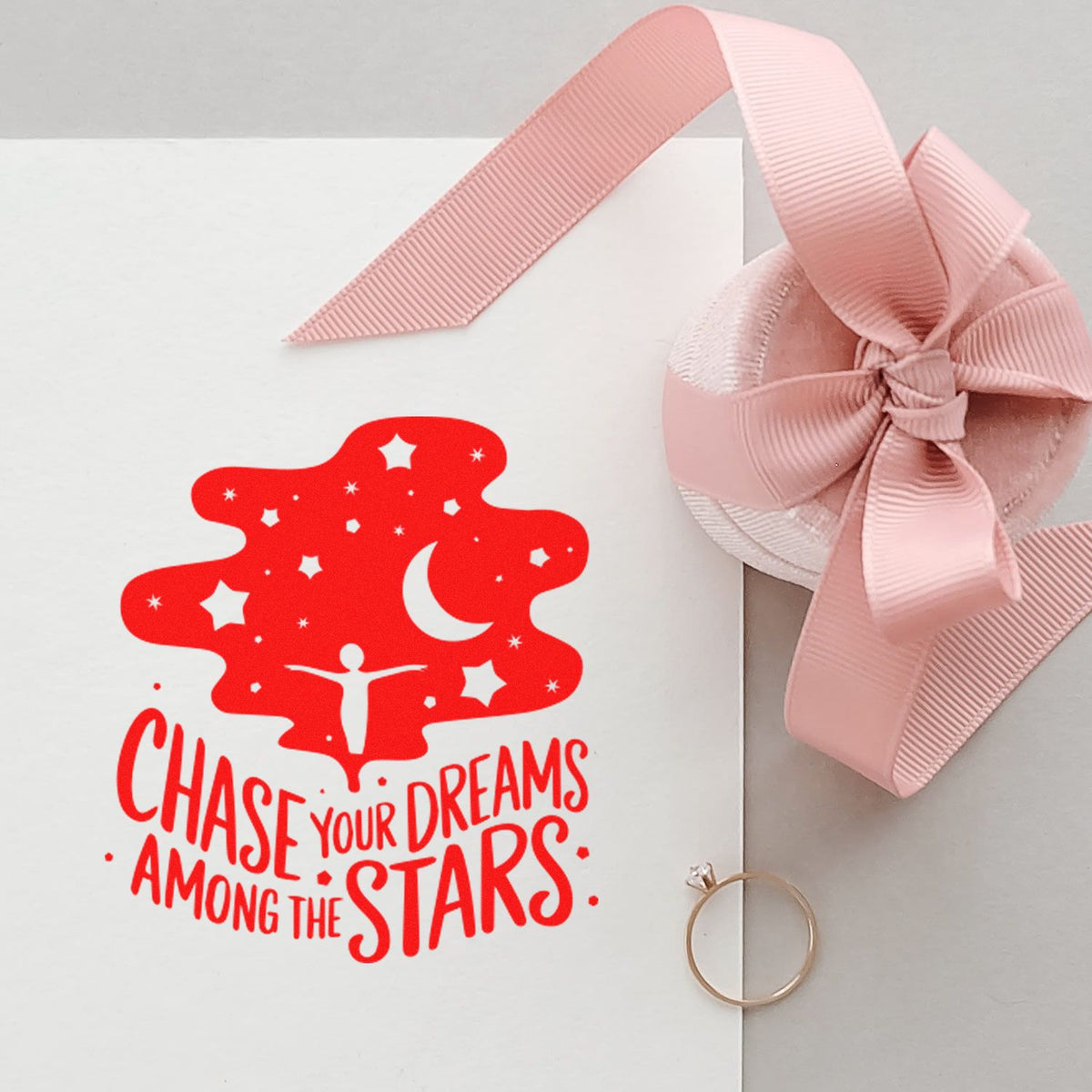 White card with red celestial stamp reading Chase your dreams among the stars, pink ribbon bow seal, and gold ring seal.