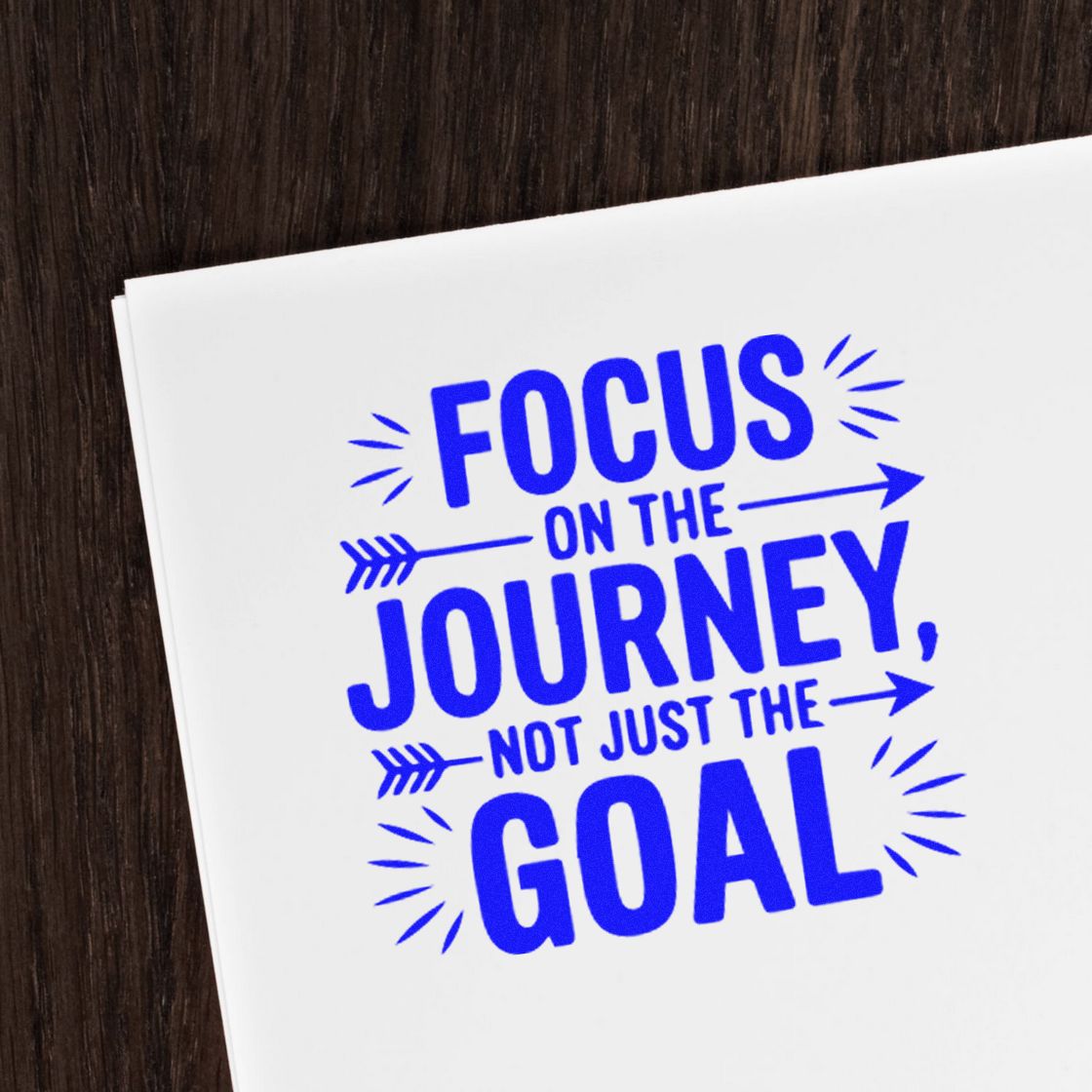 Blue rubber stamp seal with Focus on the Journey, Not Just the Goal and arrow accents on white paper.