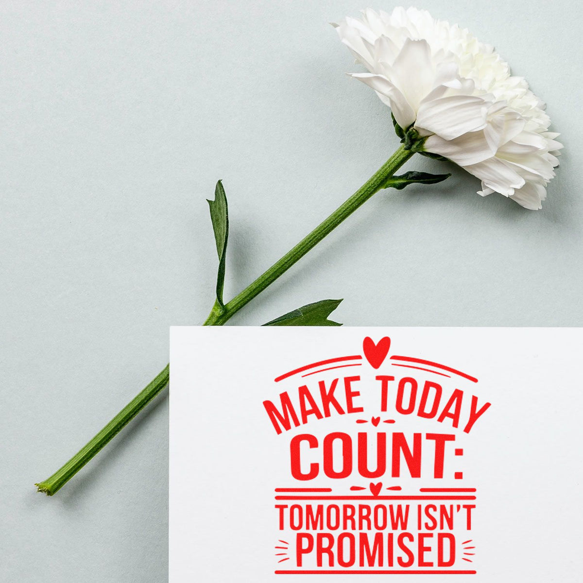 White flower stem beside a white stamp card with bold red seal reading Make Today Count: Tomorrow Isnt Promised