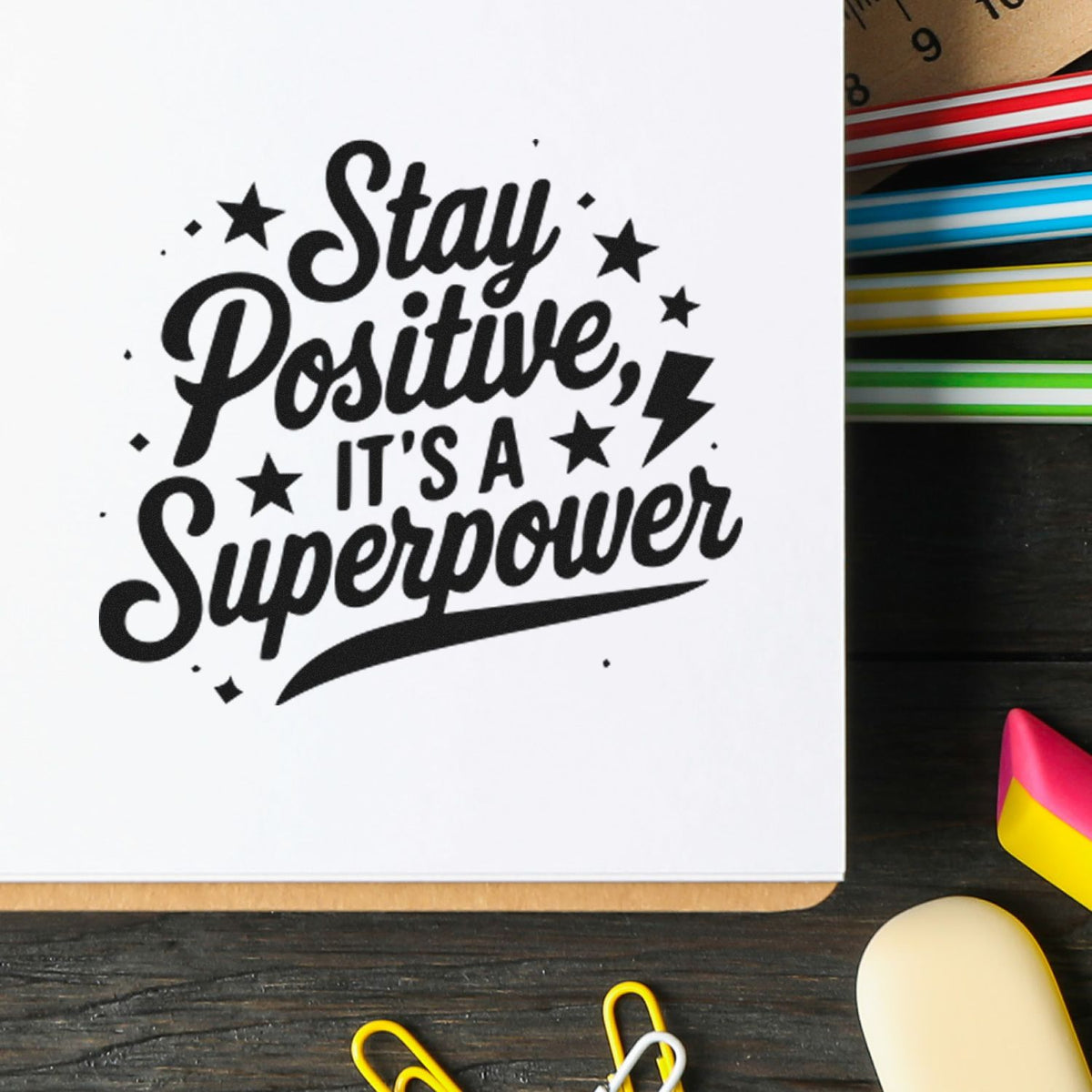 Black motivational stamp reading Stay Positive, Its a Superpower with stars, lightning, and colorful seal tools on white.