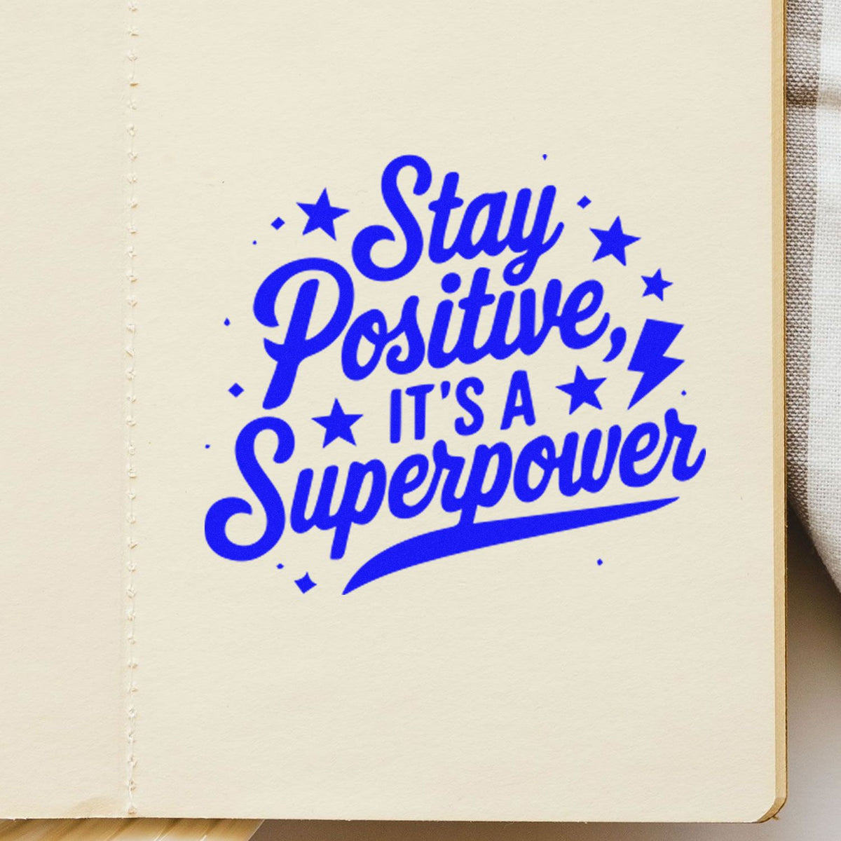Blue decorative stamp seal reading Stay Positive, Its a Superpower with stars and a lightning bolt.
