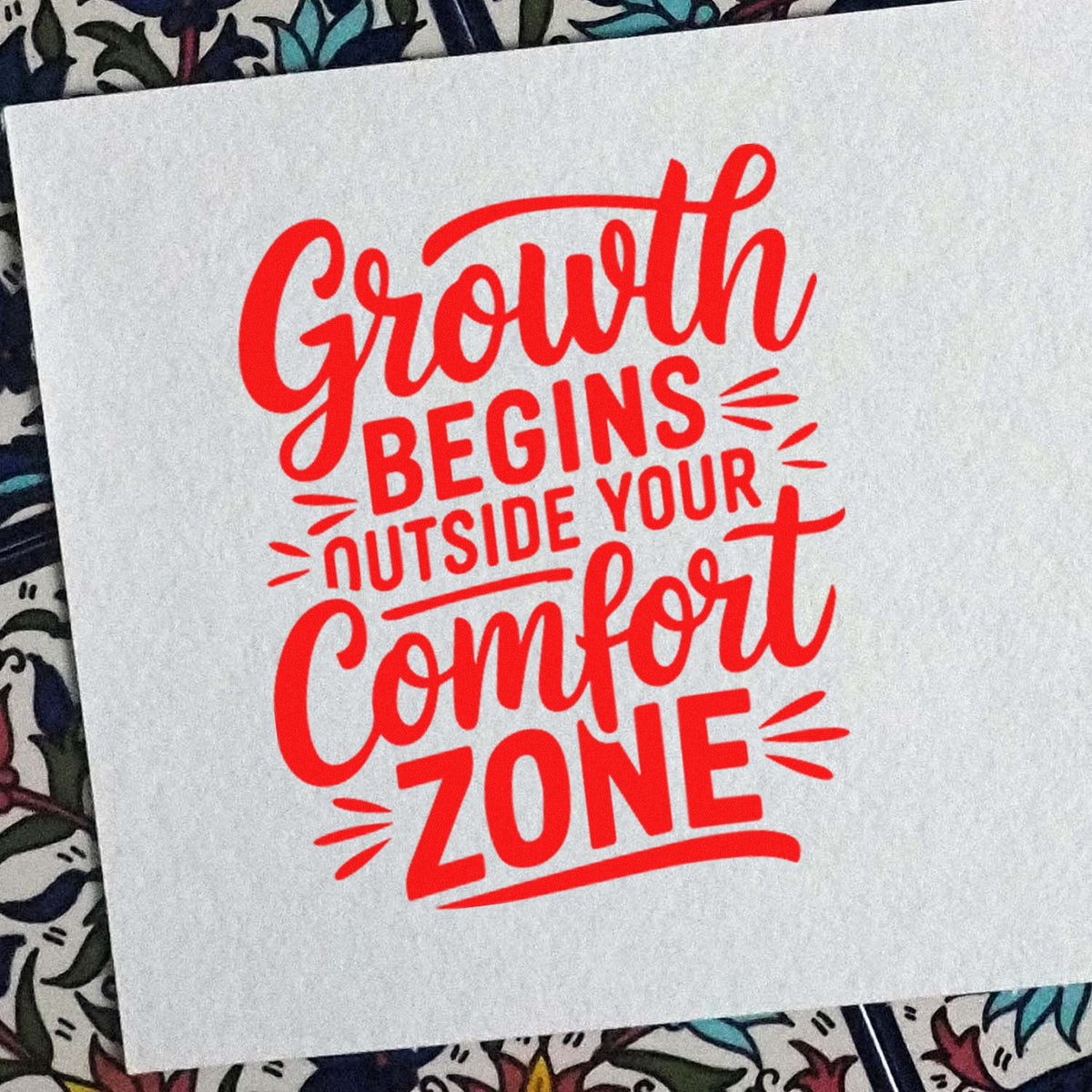 Red motivational stamp seal reading Growth begins outside your comfort zone on white paper.