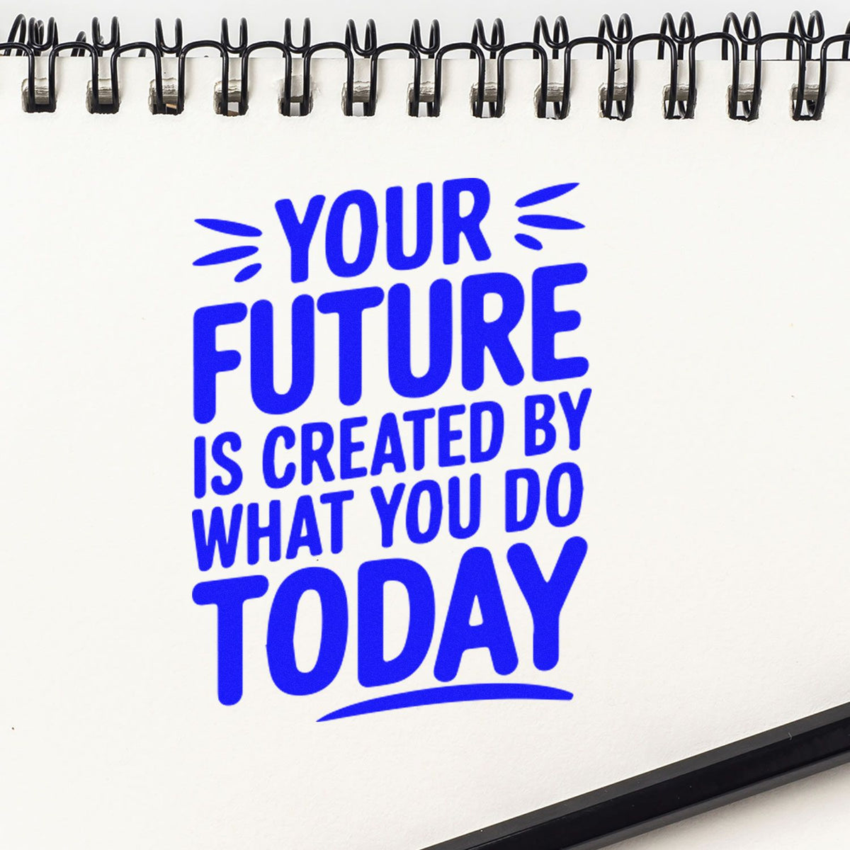 White spiral-bound stamp and seal planner with bold blue motivational quote about creating your future today.