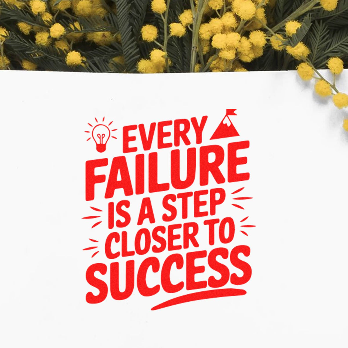 Red stamp seal reading Every failure is a step closer to success on white background, with yellow flowers above.