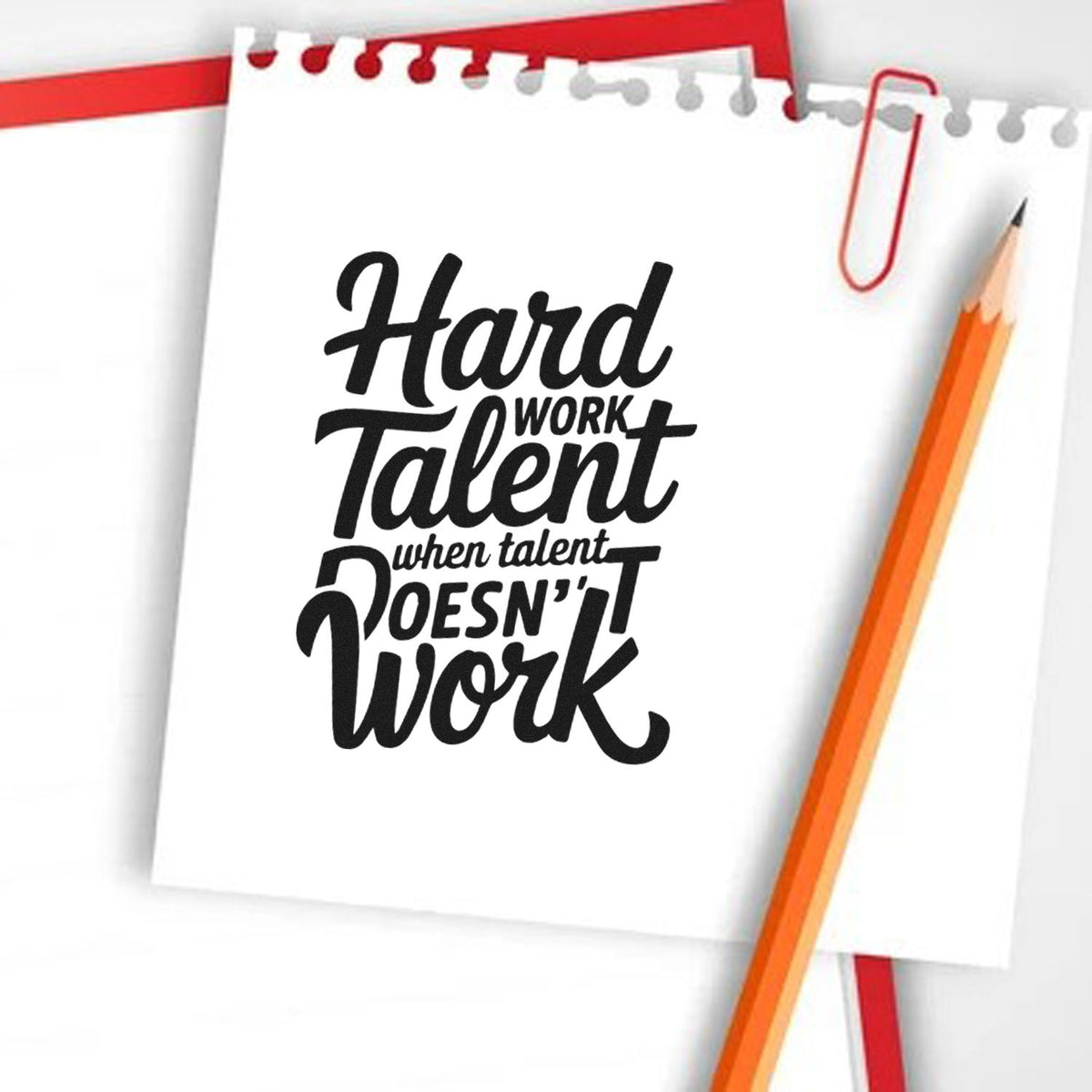 Black motivational stamp seal reading Hard Work Talent on white notepad, with red clips and orange pencil