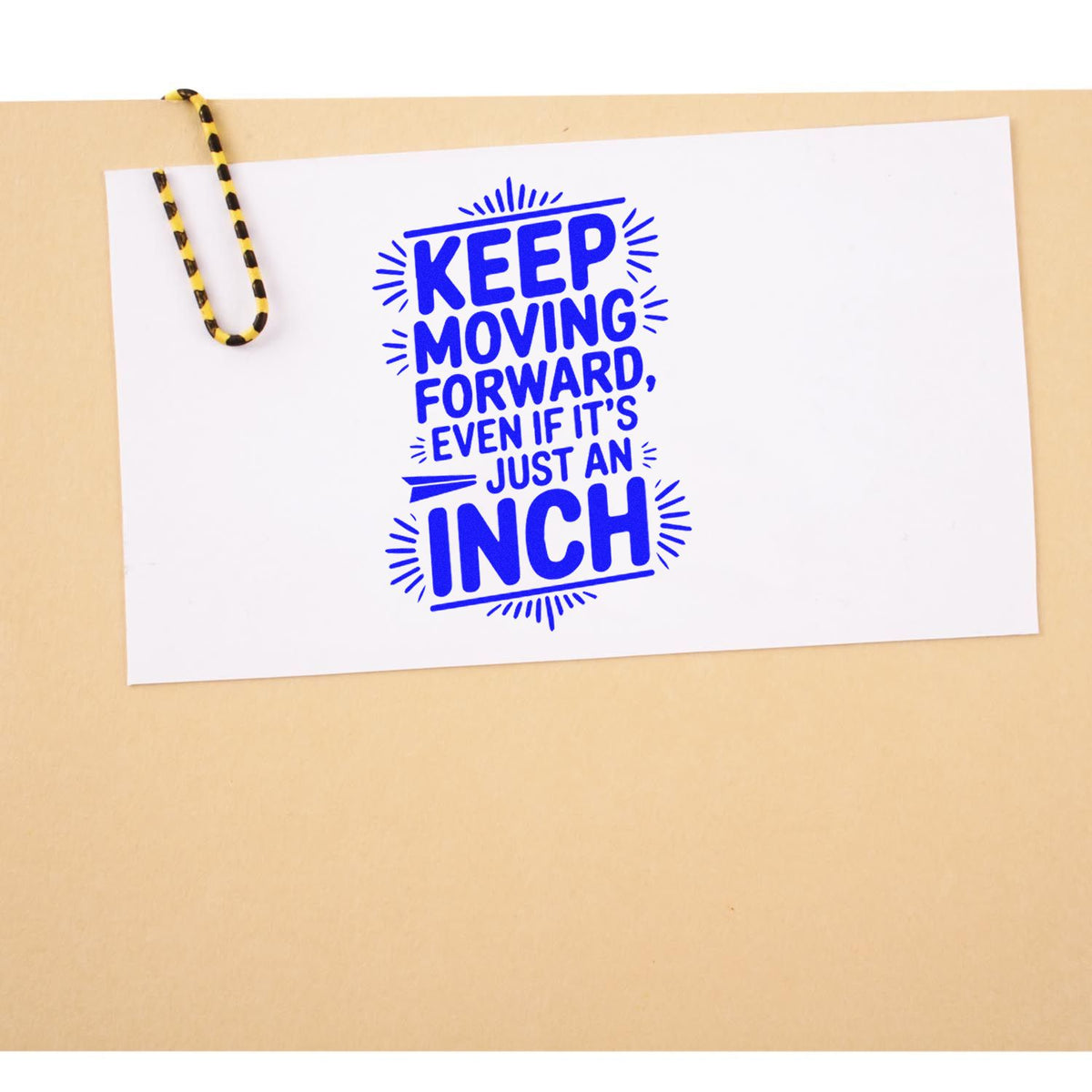 Blue custom stamp and seal on white card reads Keep moving forward, even if its just an inch, clipped with black-and-yellow paperclip.