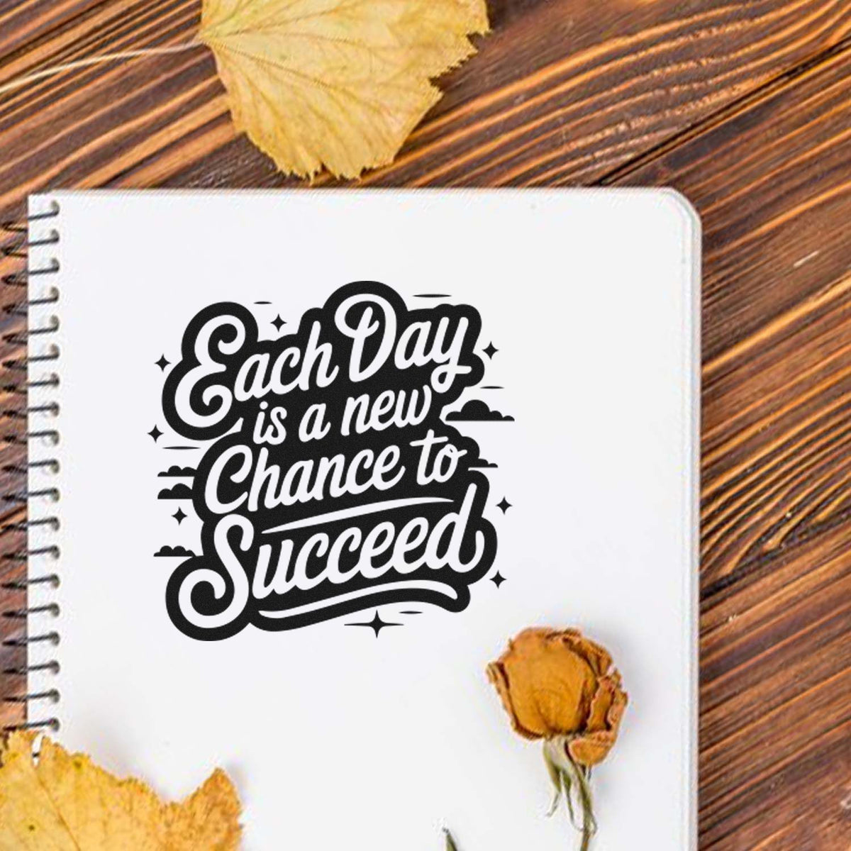 Black motivational stamp seal reading Each Day is a new Chance to Succeed on a white notebook page with autumn leaves.
