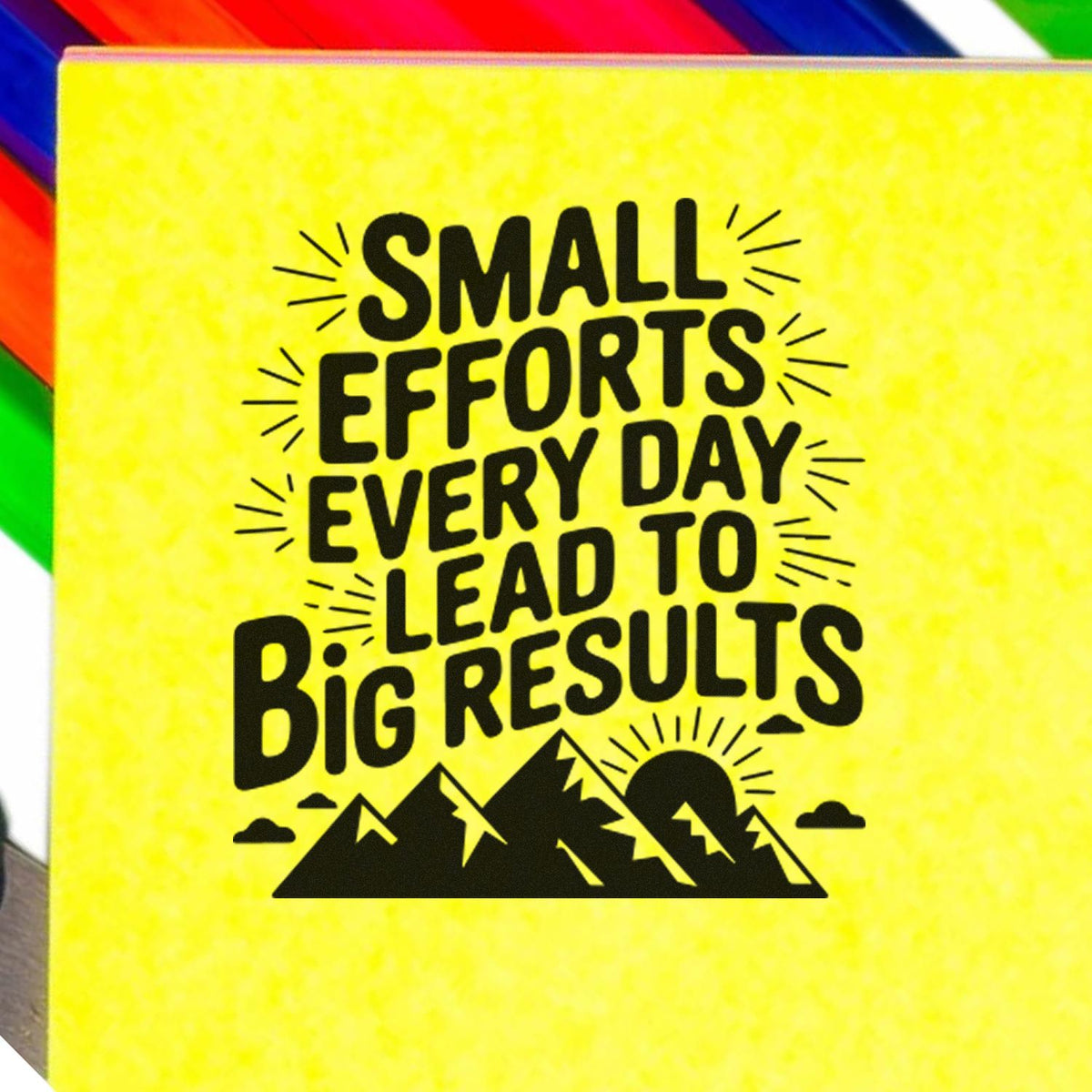 Yellow rubber stamp seal with black Small efforts every day lead to big results text, mountain graphic, and rainbow edge accents.