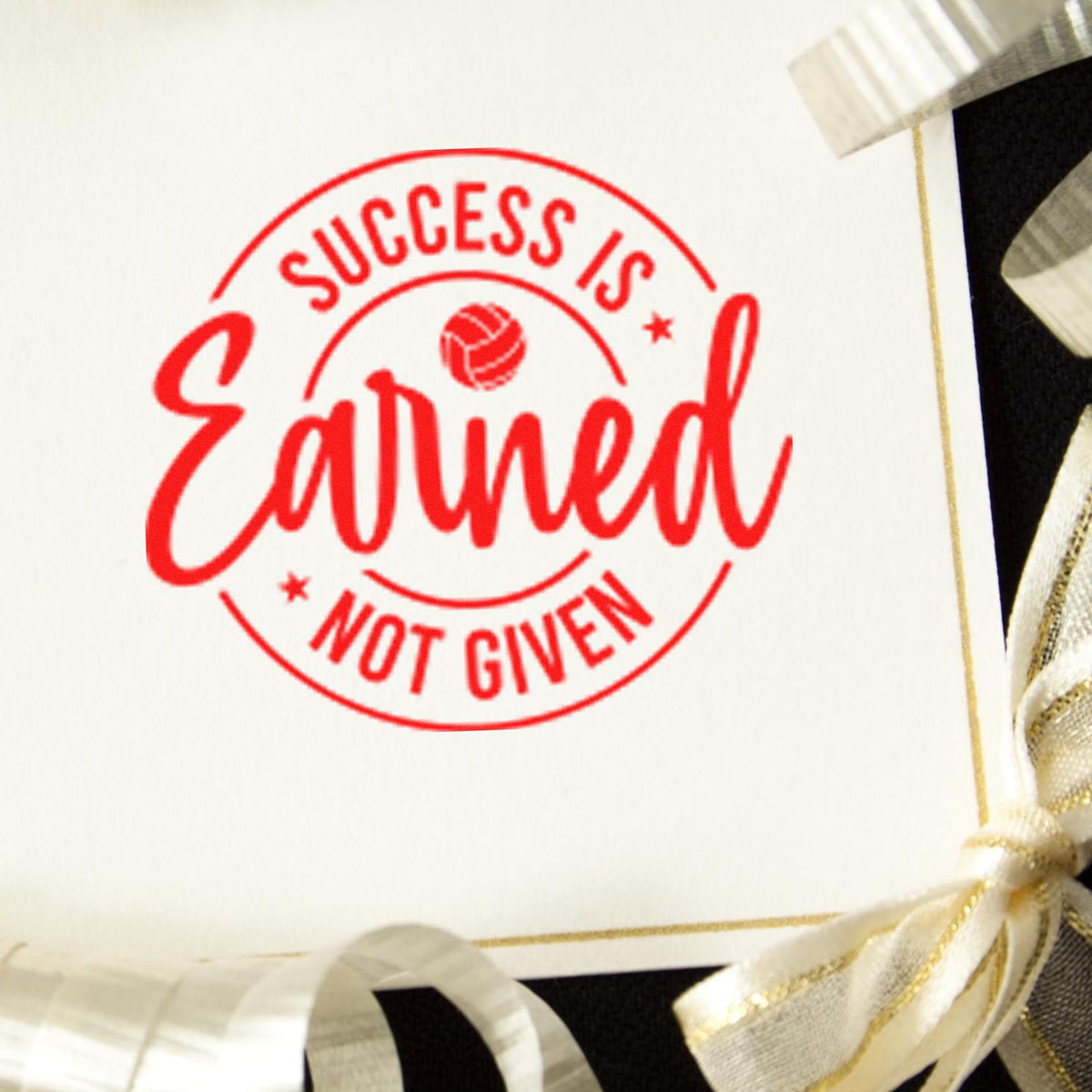 Red Success is Earned, Not Given circular stamp seal on white card with gold ribbon accents.